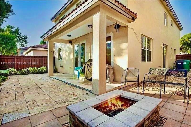 Covered patio with recessed lighting, stone-tiled flooring, and a built-in stone-surround fire pit