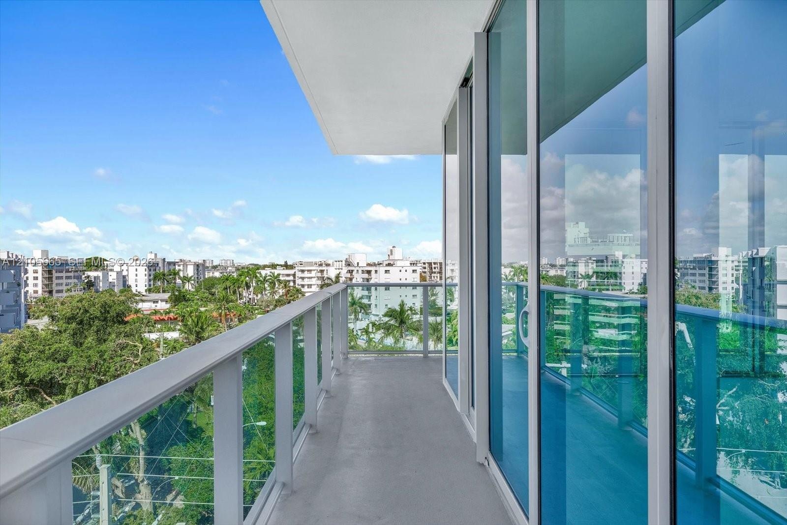Private balcony featuring a glass-panel railing, floor-to-ceiling windows, and concrete flooring