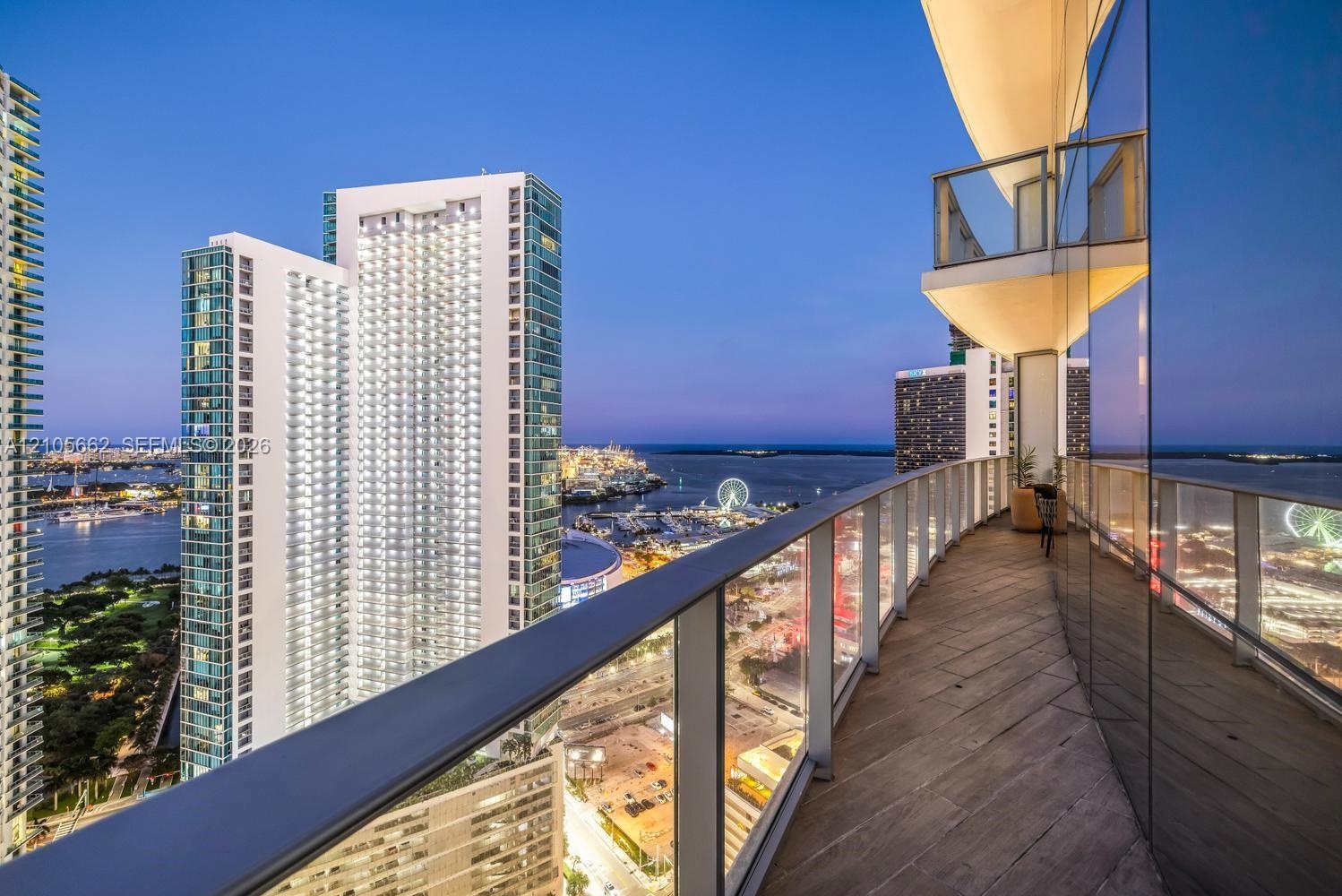 Curved wrap-around balcony featuring wood-finish tile flooring, floor-to-ceiling glass wall, and glass-paneled metal railing