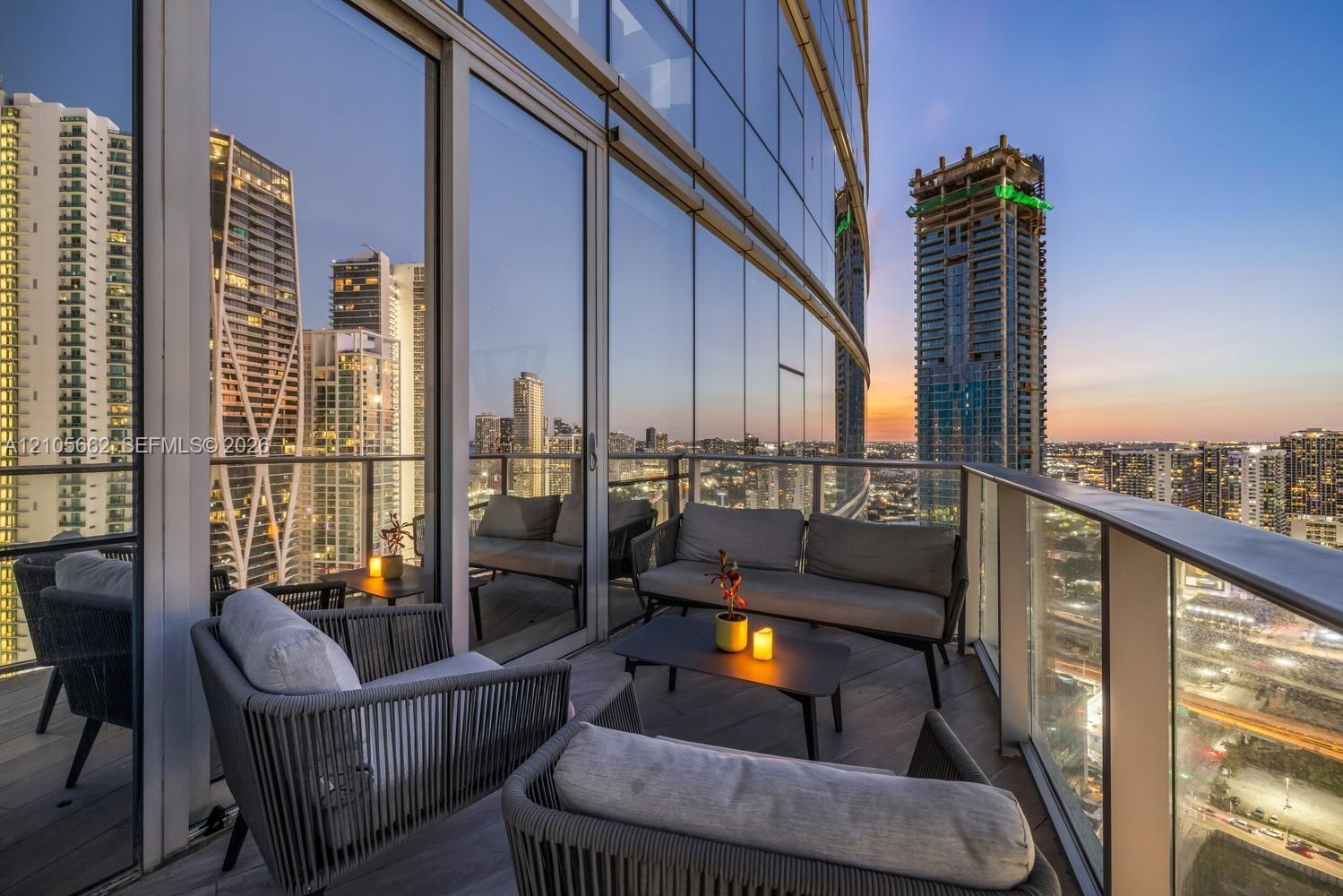 Covered balcony featuring floor-to-ceiling glass walls, wood-finish decking, and a glass-paneled railing