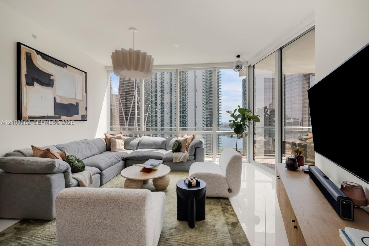 Floor-to-ceiling windows, polished tile flooring, pendant lighting, and an expansive balcony