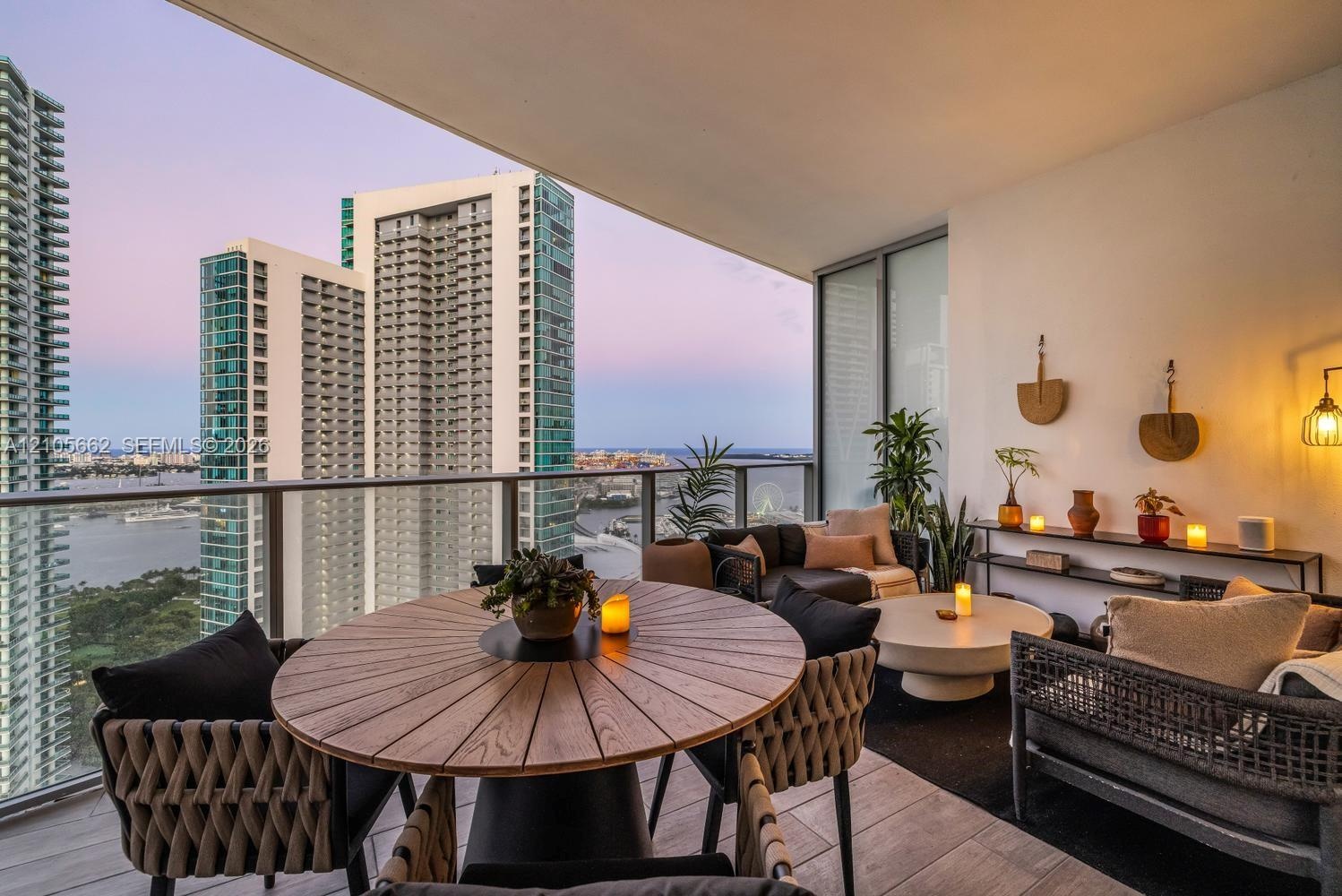 Covered outdoor balcony featuring tile flooring, glass panel railings, and urban skyline scenery