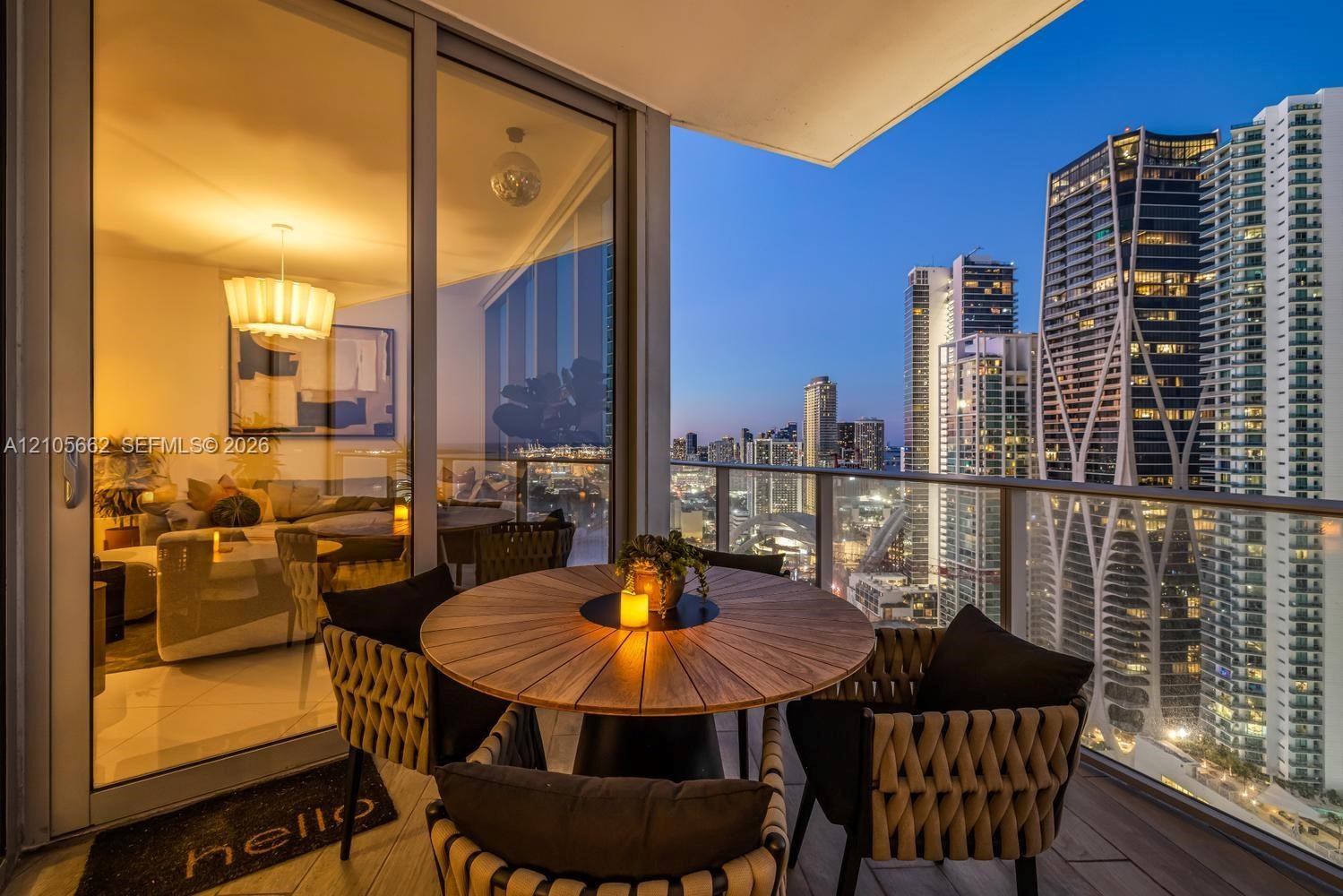 Covered balcony featuring wood-finish flooring and a glass railing with metal trim