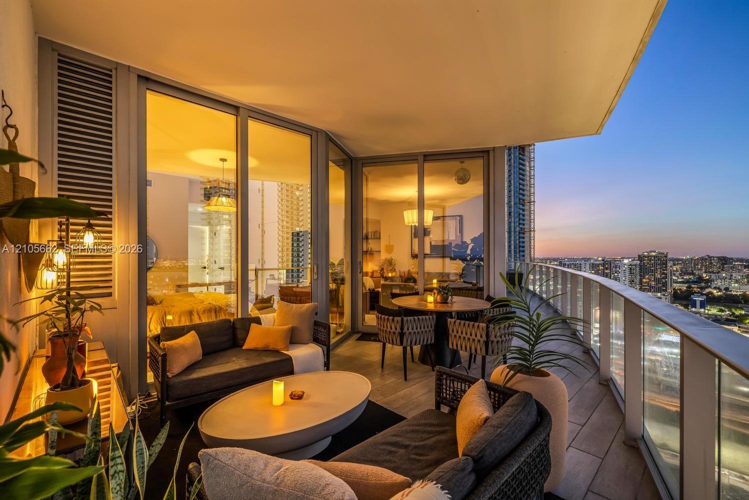 Covered balcony featuring wood-finish tile flooring, glass panel railings, and floor-to-ceiling sliding glass doors