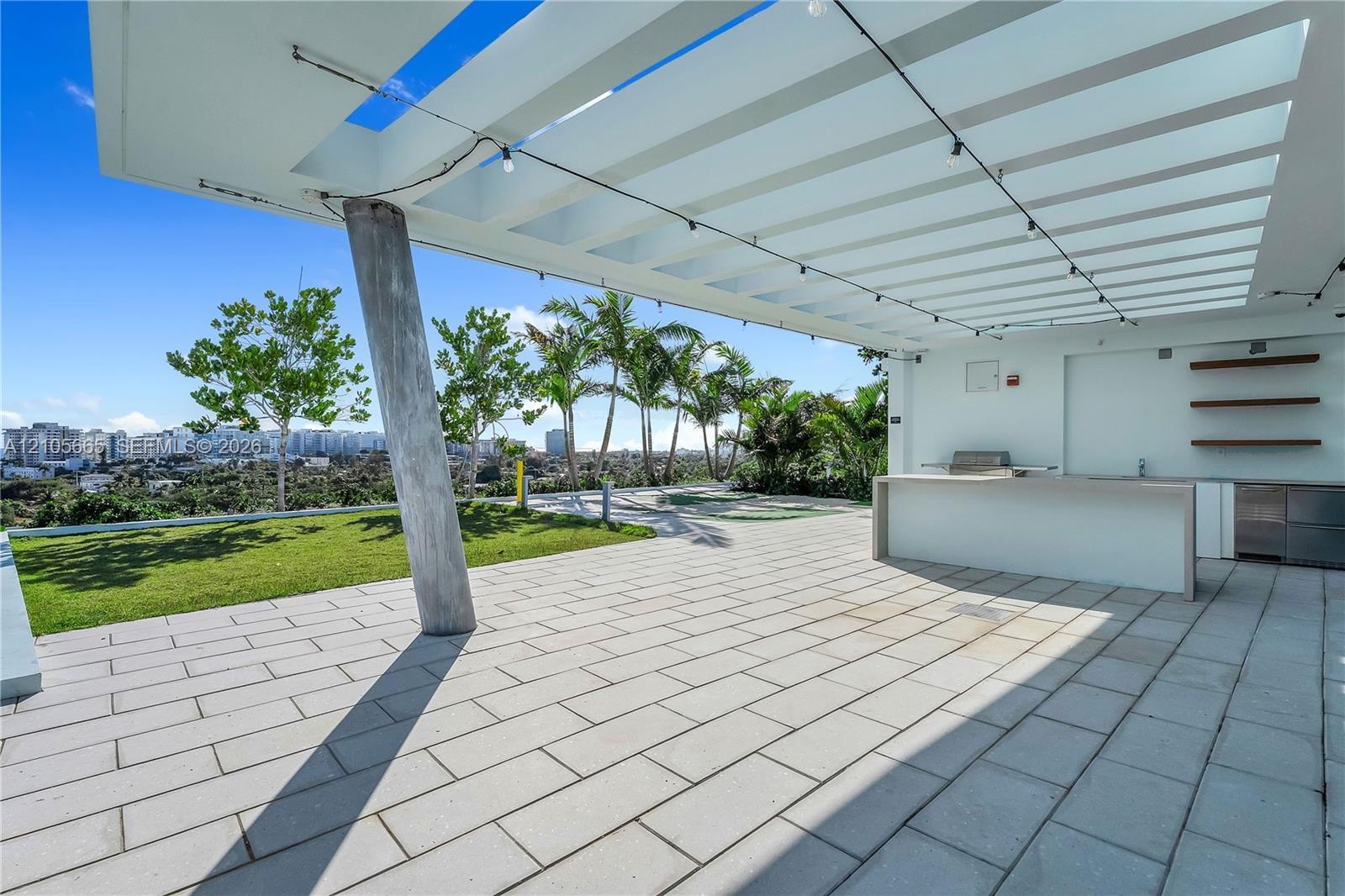 Outdoor terrace featuring a pergola with integrated string lighting, paved flooring, built-in kitchen counter, and open-air shelving
