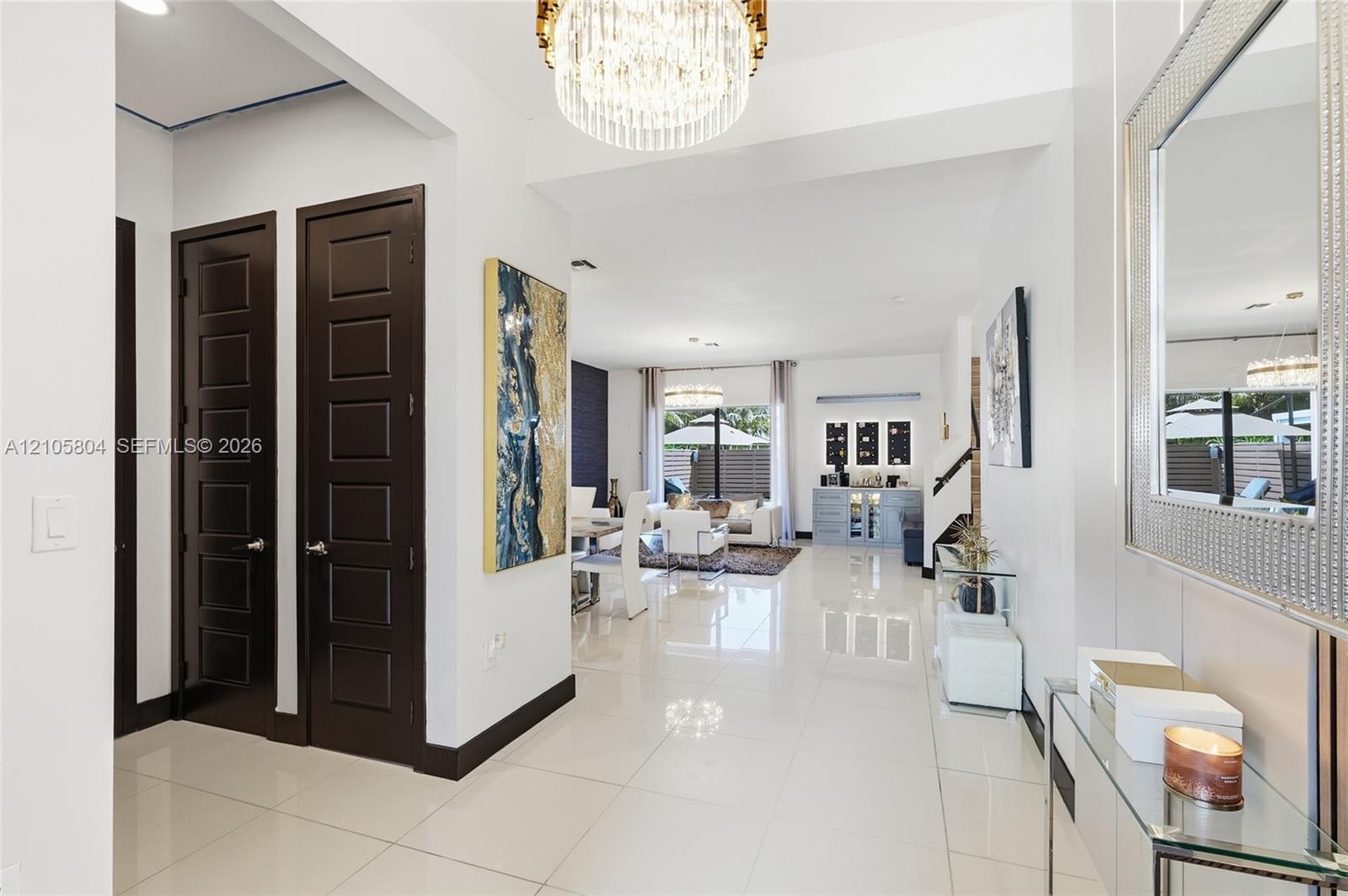 Polished porcelain tile flooring, dark-toned six-panel interior doors, and a multi-tiered crystal drum chandelier