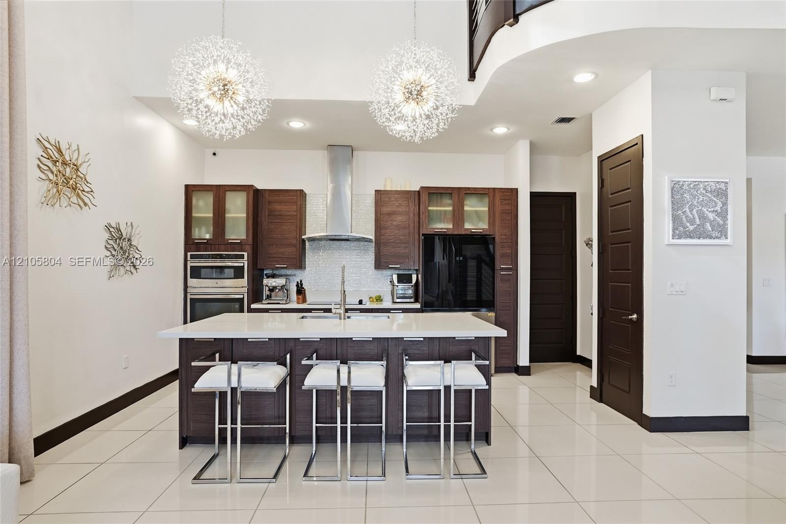 Kitchen featuring dark wood-finish cabinetry, a white stone island countertop, a stainless steel chimney-style range hood, recessed ceiling lighting, 