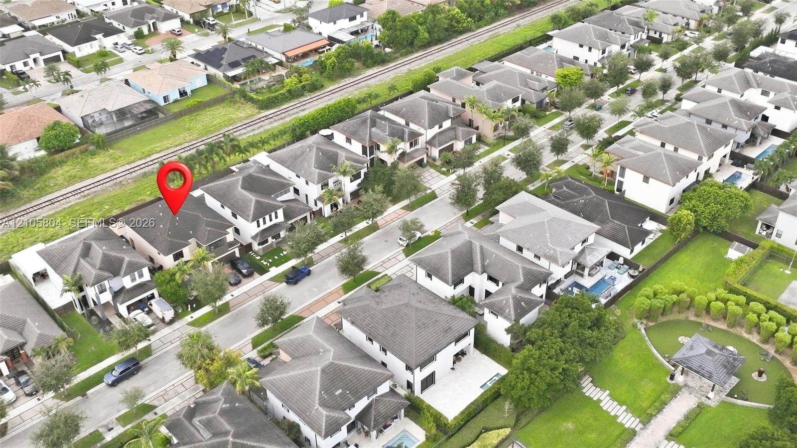 Aerial perspective of a multi-story residence featuring a hipped roof, attached garage, paved driveway, and manicured landscaping