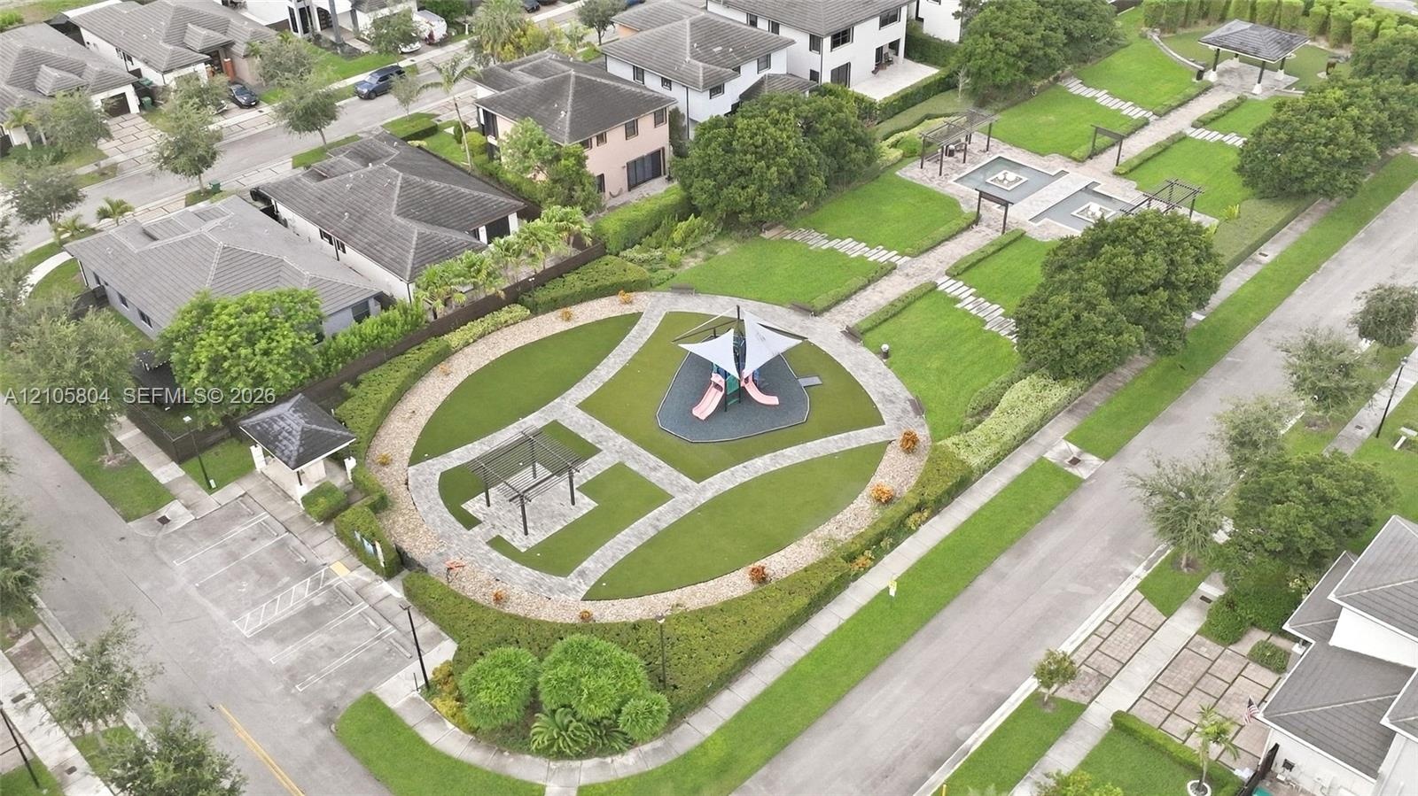 Expansive outdoor grounds featuring manicured lawns, paved pathways, a covered playground structure, multiple pergolas, and structured hedges