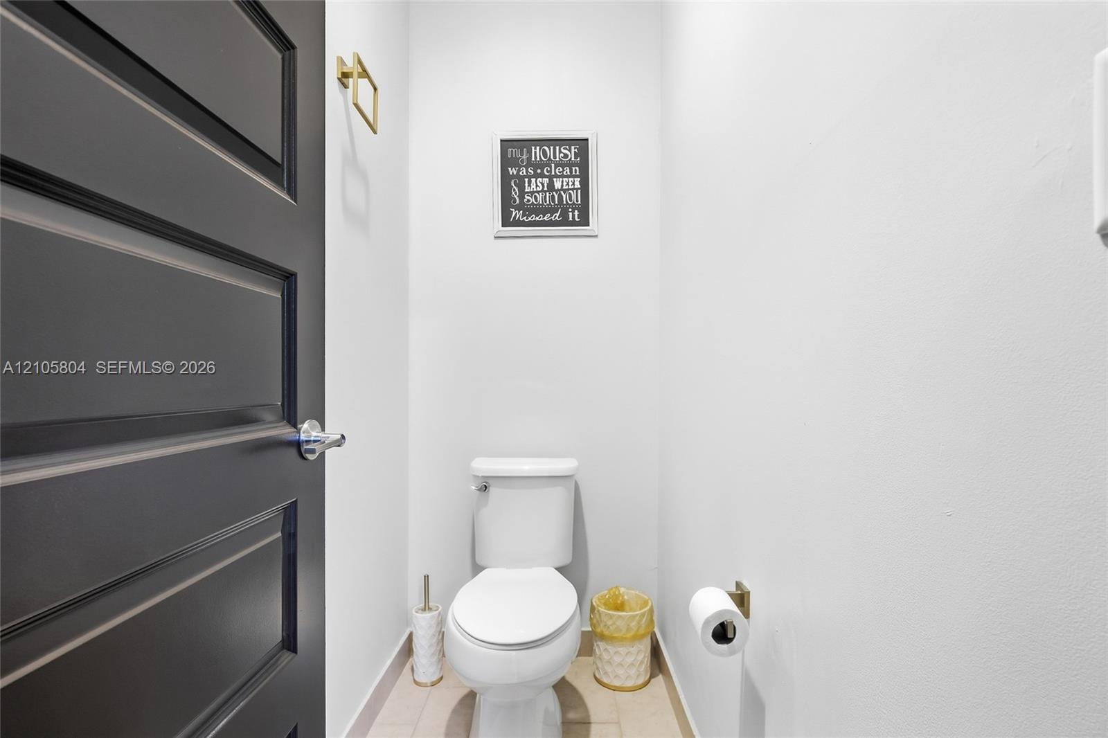 Powder room featuring a matte black paneled door, gold-tone hardware, and a high-profile toilet