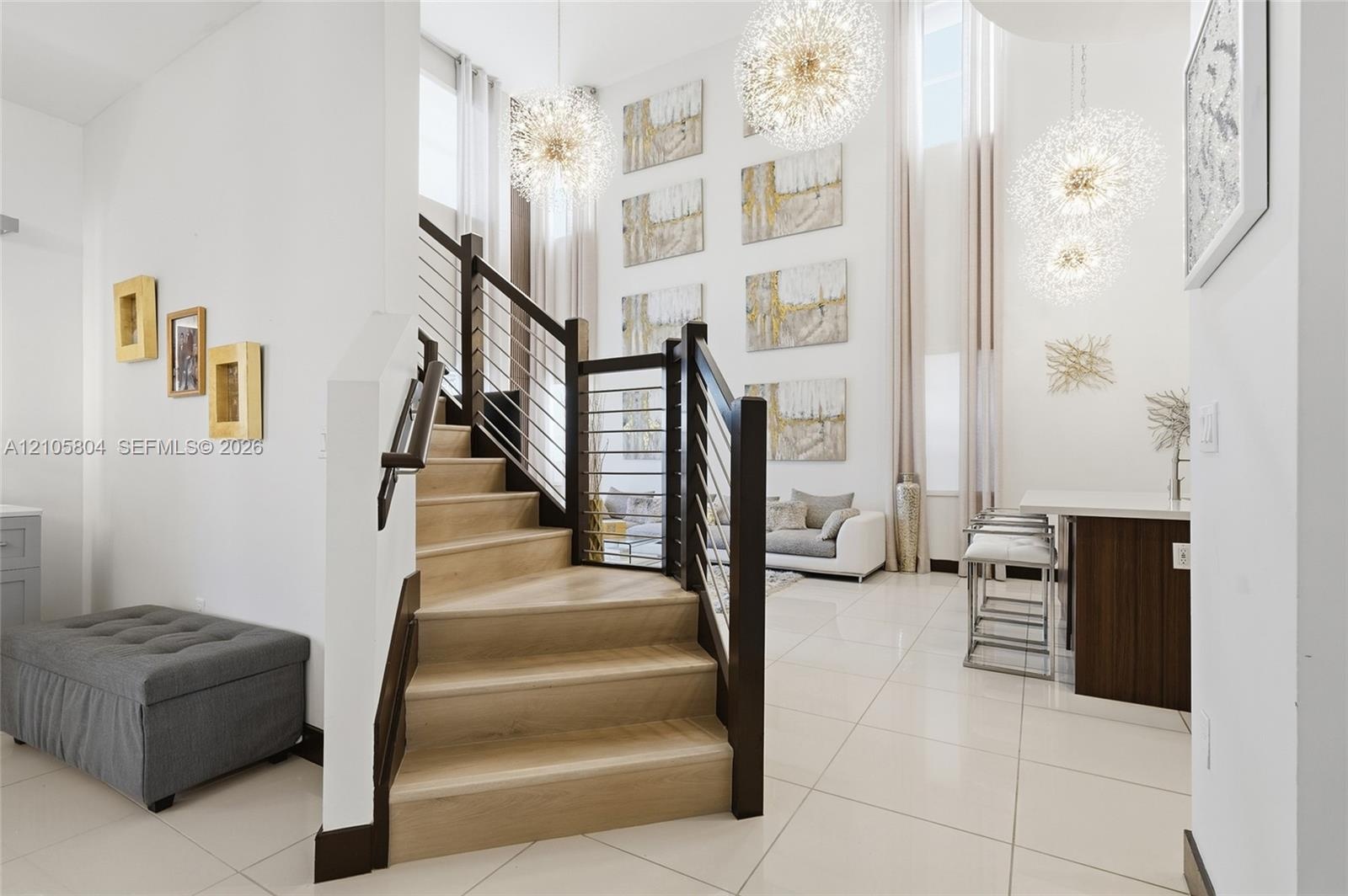Staircase featuring wood-finish treads, dark wood posts, and a cable railing system, complemented by high-gloss floor tile and suspended globe-style p