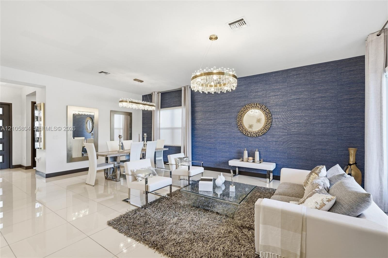 Polished tile flooring, textured navy blue accent wall, and two multi-tiered crystal chandeliers