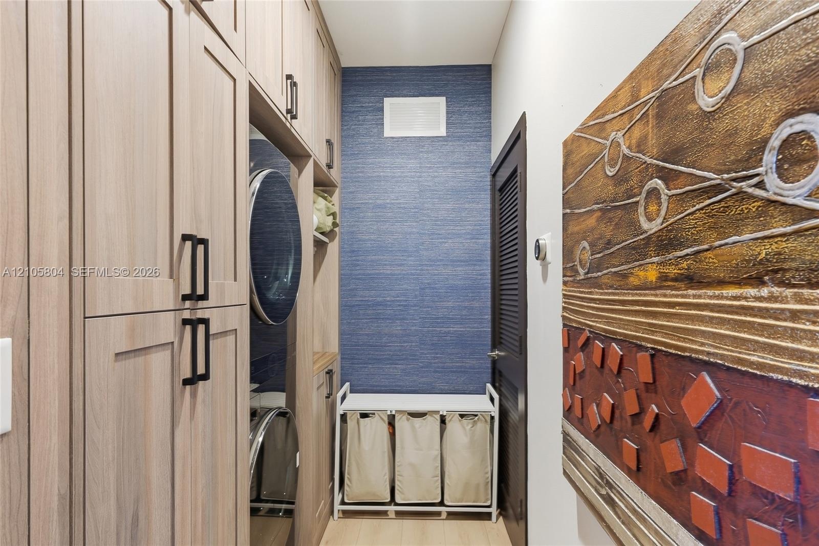 Custom floor-to-ceiling cabinetry with matte black hardware, integrated laundry appliances, and textured blue accent wall