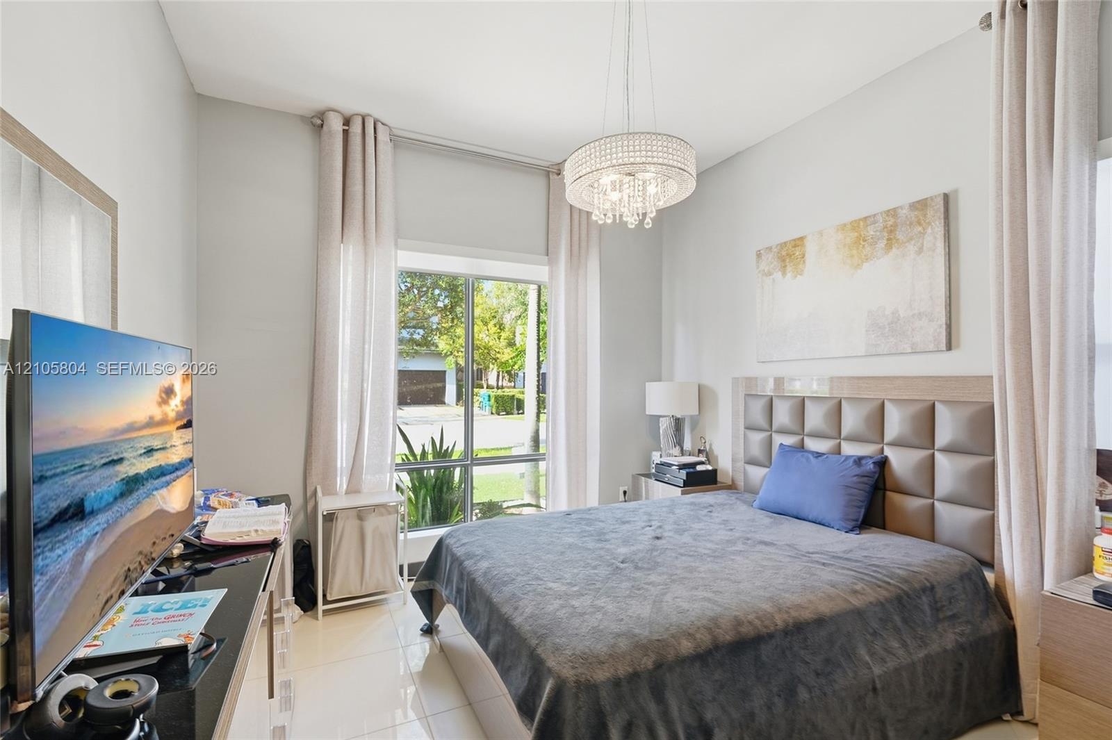 High-ceilinged room featuring oversized window panels, glossy tile flooring, and a crystal-accented chandelier fixture