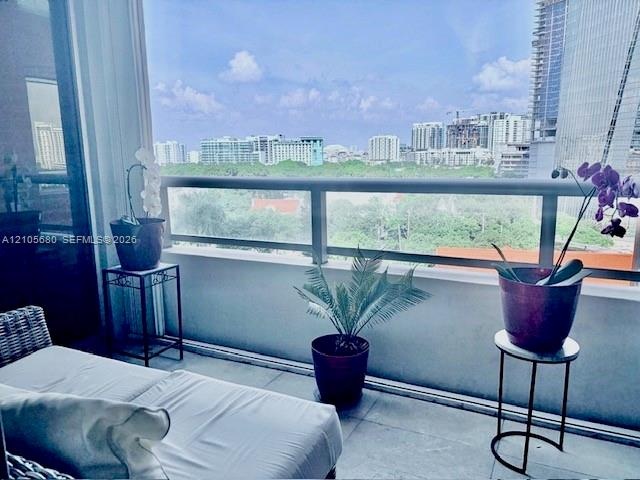 Private balcony featuring a concrete floor, solid masonry wall, and glass-paneled metal railing overlooking an urban skyline