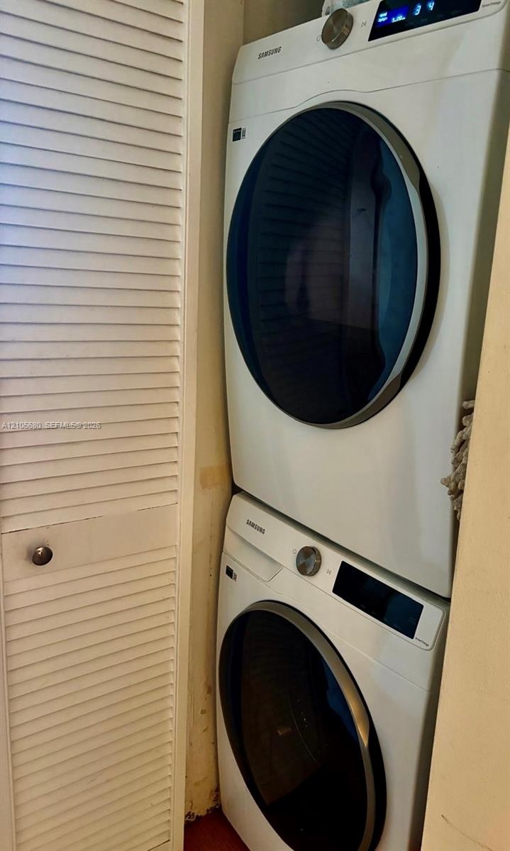 Stacked, front-load washer and dryer unit enclosed by white louvered doors