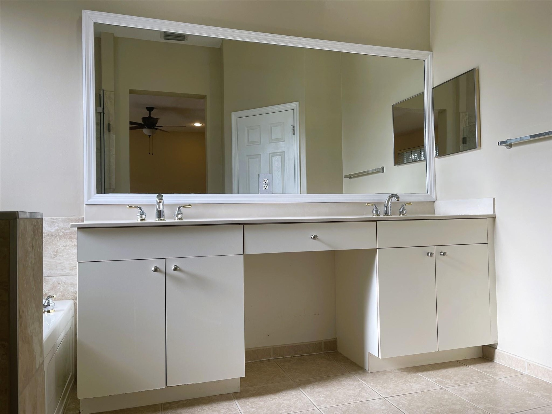 Dual-sink vanity with white cabinetry, light-toned countertop, and expansive framed wall mirror