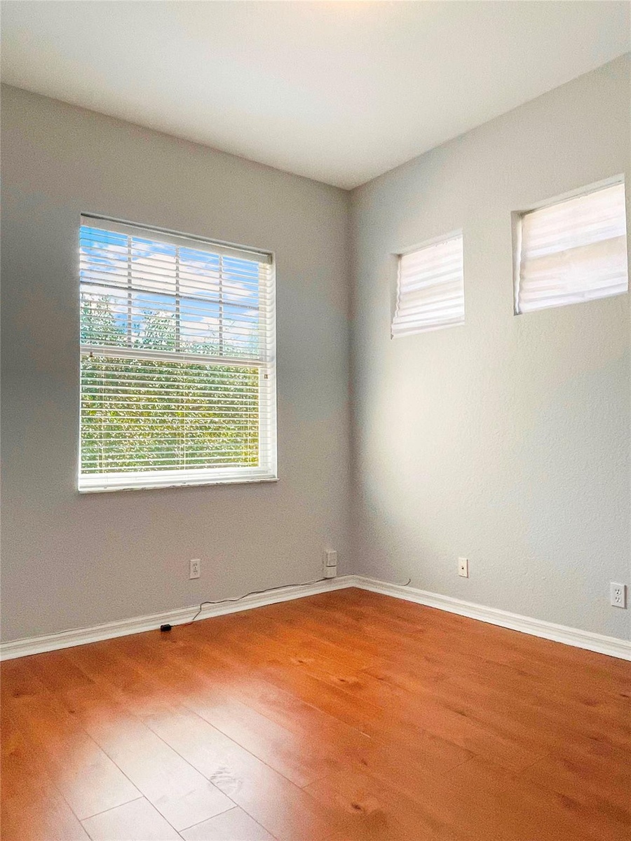 Neutral-toned walls featuring wood-finish flooring, a large dual-pane window, and two elevated transom windows