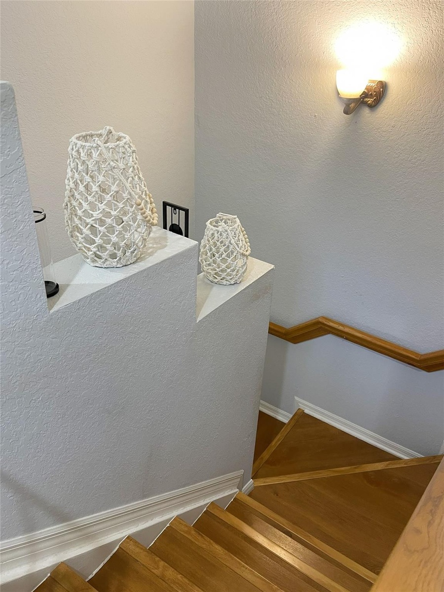 Staircase featuring wood treads, a wall-mounted wood handrail, and a wall-mounted light fixture
