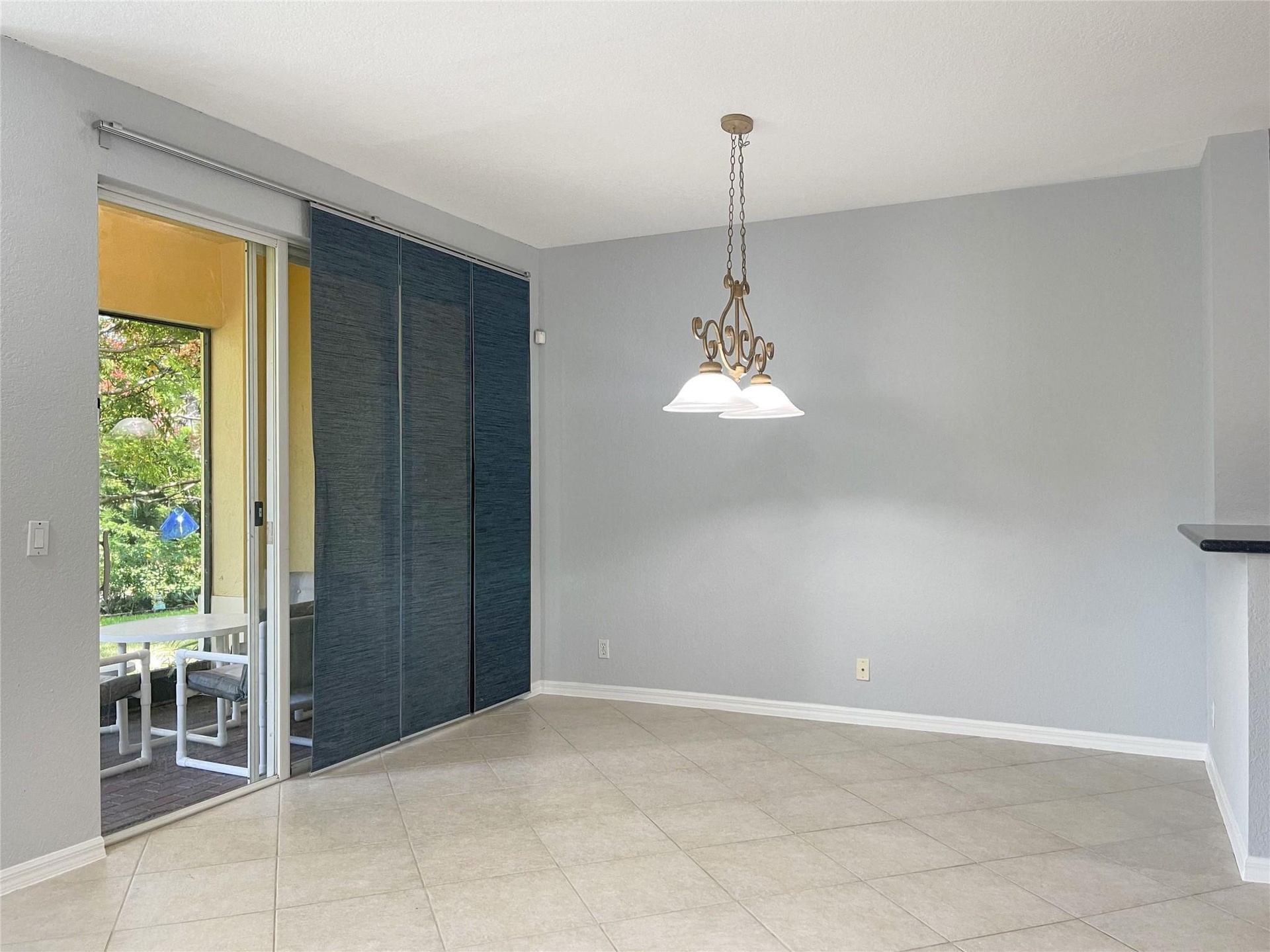 Ceramic tile flooring, sliding glass door with integrated panel blinds, and a decorative multi-light chandelier