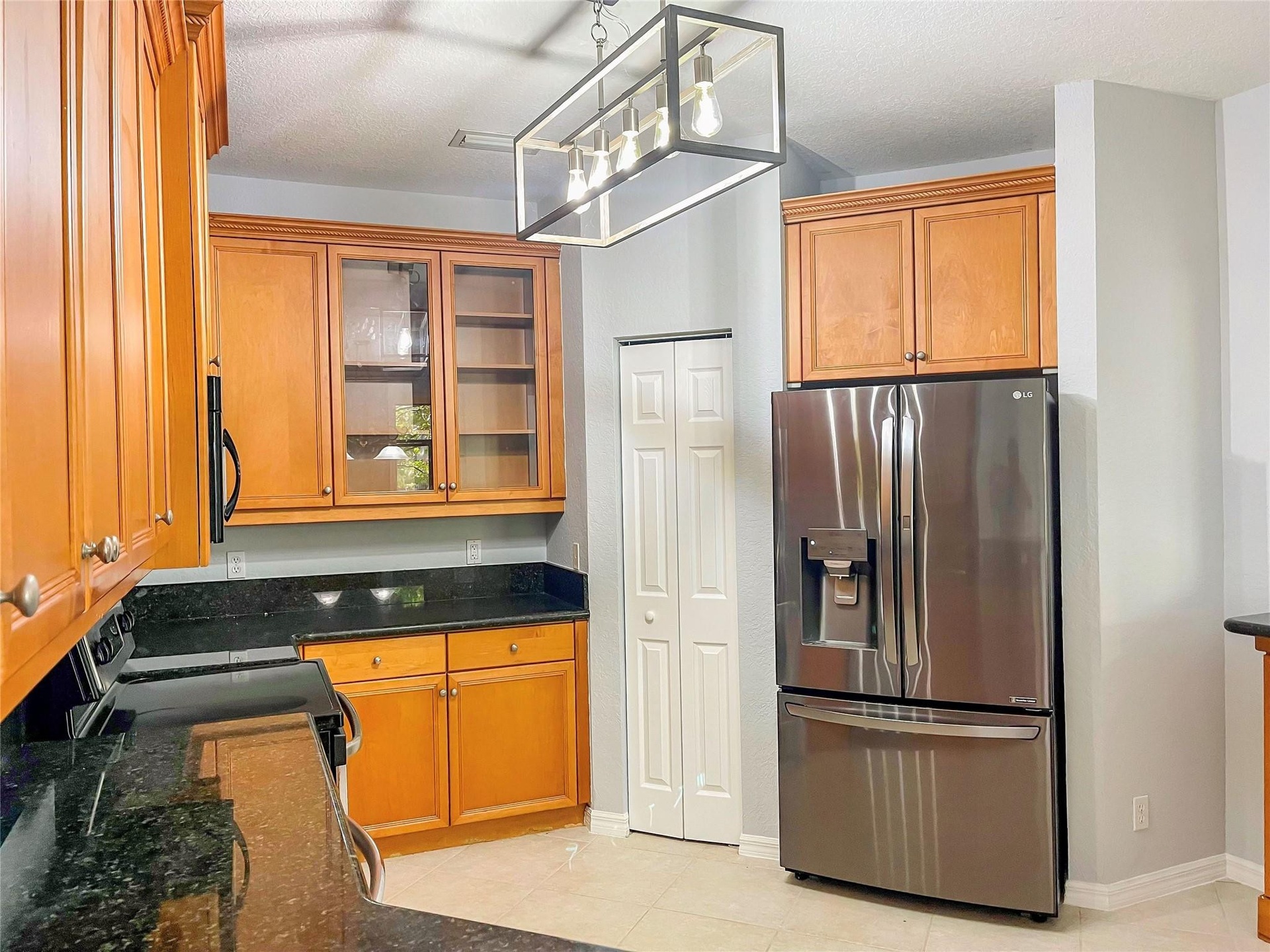 Kitchen featuring wood cabinetry, stone countertops, stainless steel French door refrigerator, glass-front upper cabinet doors, and a rectangular meta