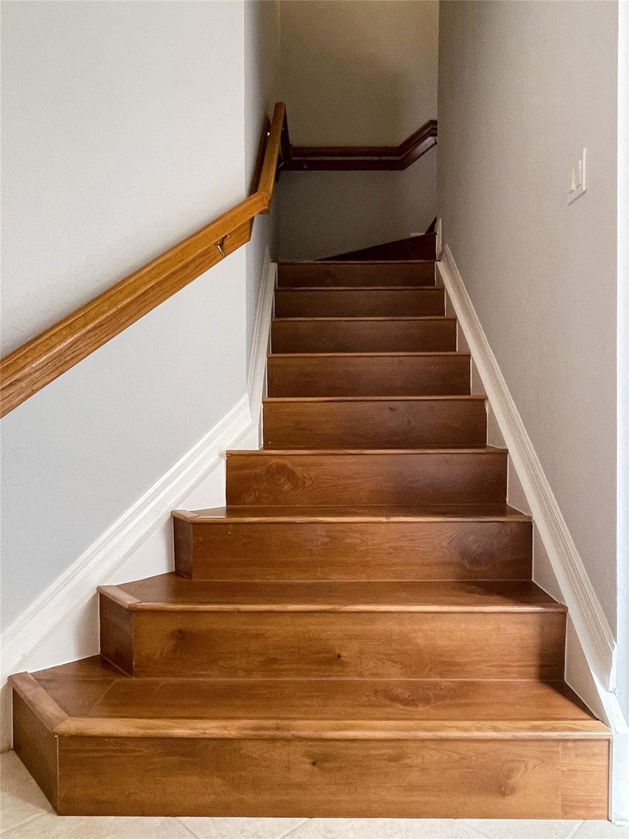 Staircase featuring wood treads and a wall-mounted wooden handrail