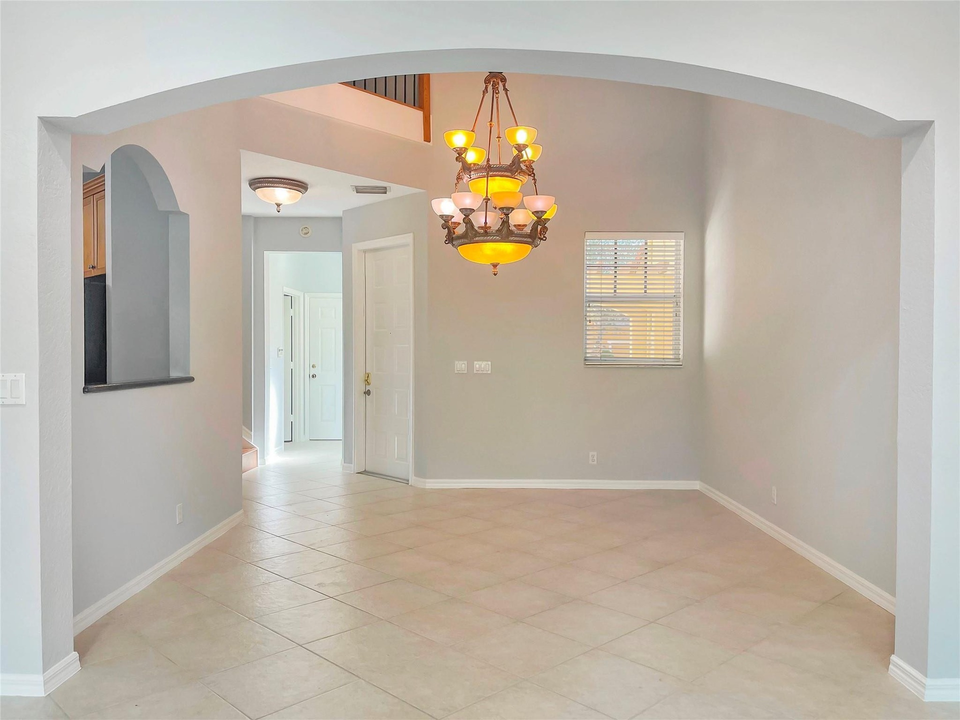 Arched entryway featuring tile flooring, a multi-tiered chandelier, a decorative wall niche, and vaulted ceilings