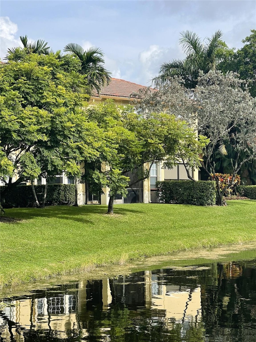 Waterfront property featuring a tiled roof, screened-in exterior space, and mature perimeter landscaping