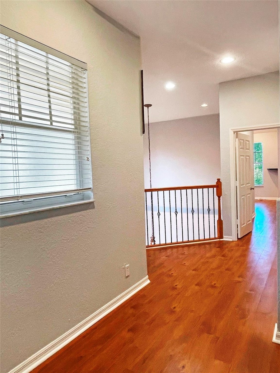Interior space featuring wood-finish flooring, recessed lighting, and a metal balustrade railing