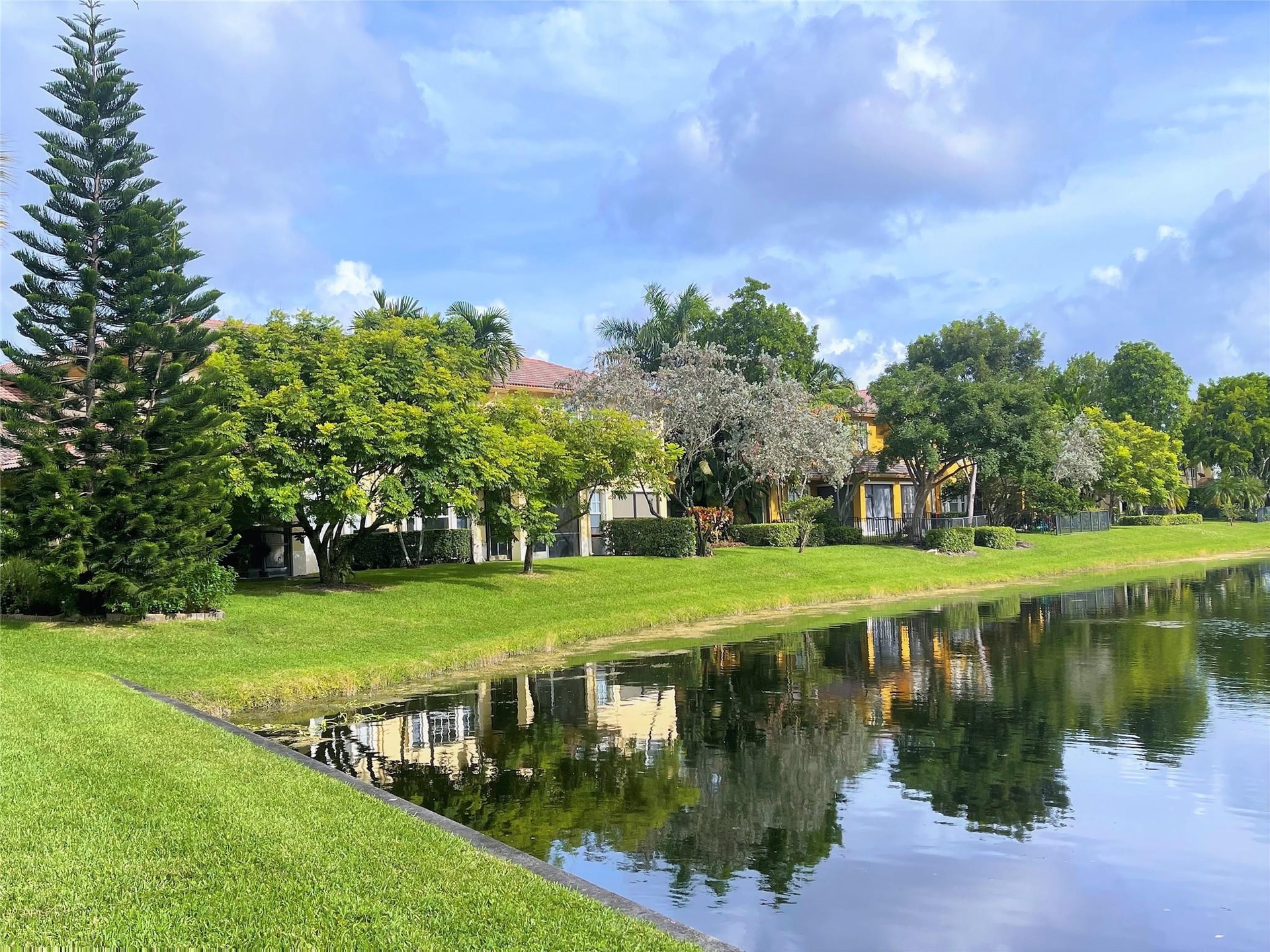 Waterfront property featuring manicured lawns, mature specimen trees, and established landscaping
