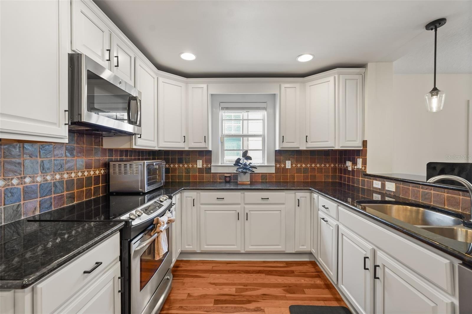 Kitchen with white cabinetry, stainless steel appliances, and tile backsplash