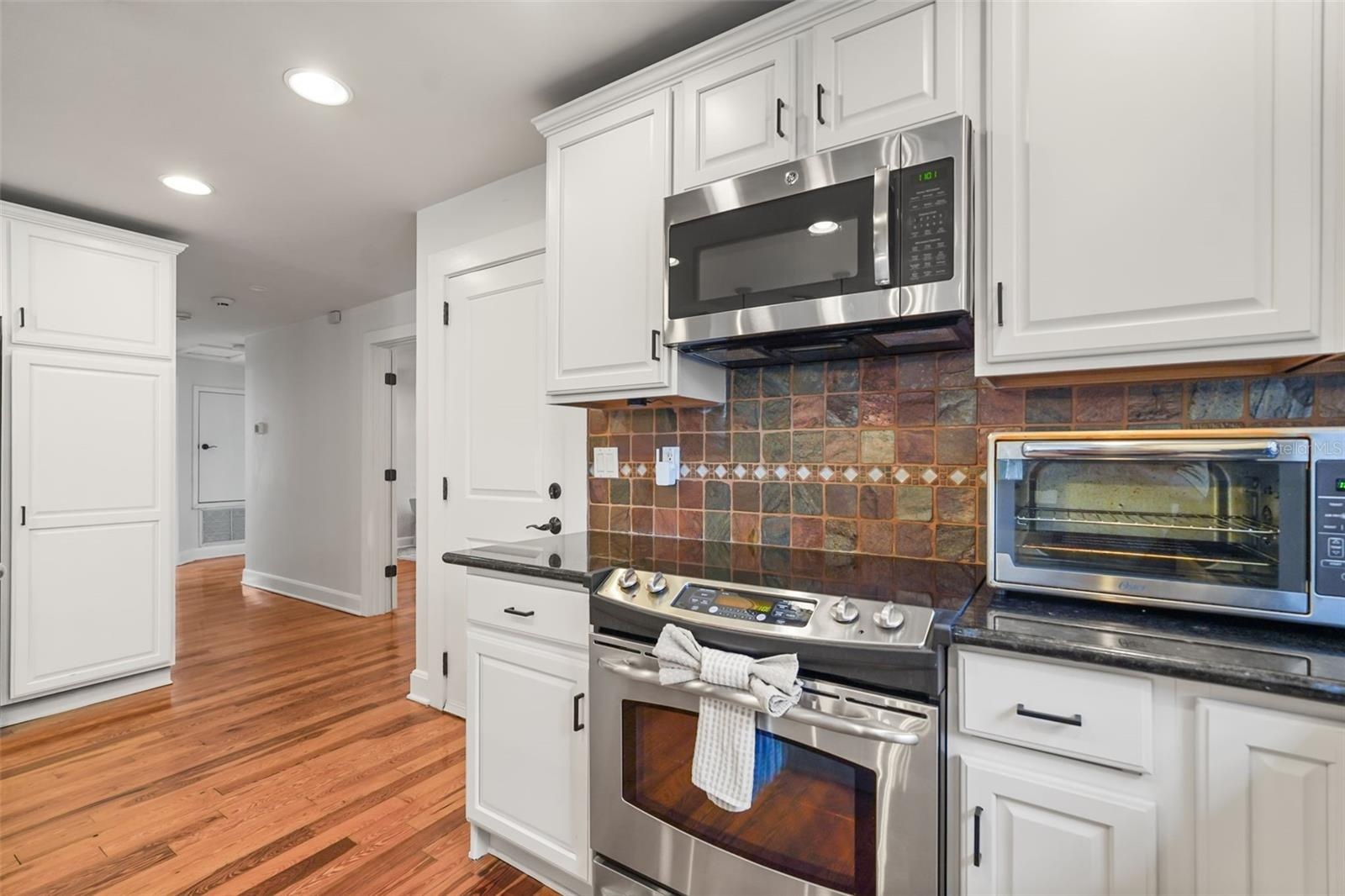 Kitchen range and cabinetry with hallway view