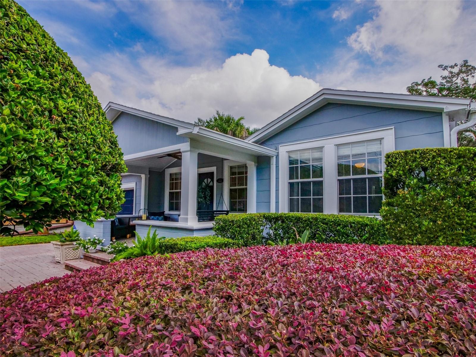 Front exterior with covered porch and flowering hedges