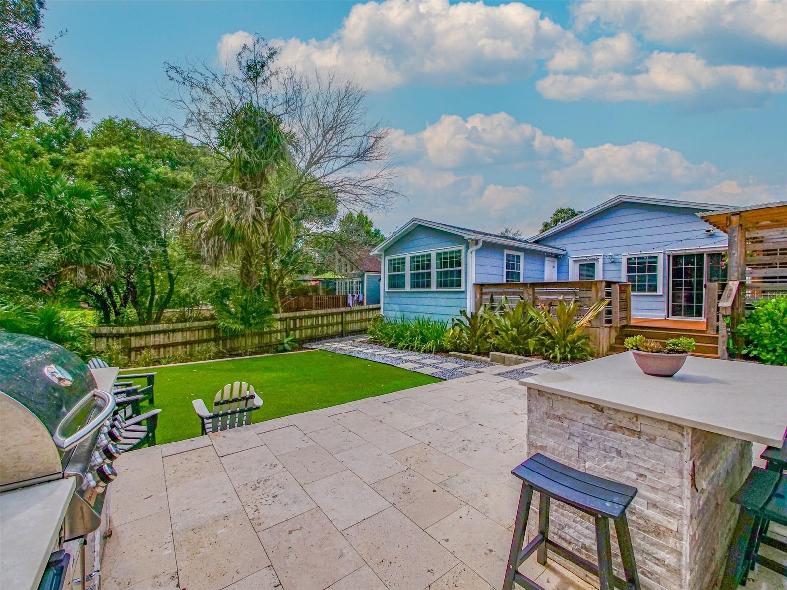 View from the outdoor kitchen across the patio and turf to the rear exterior