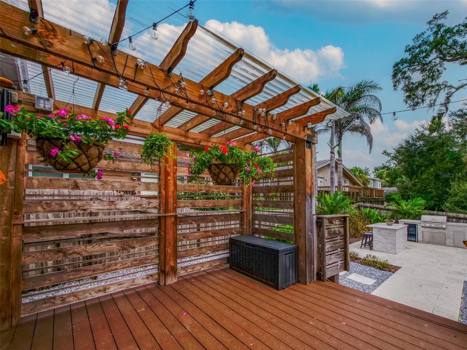 Rear deck with pergola, string lights, and view of the outdoor kitchen