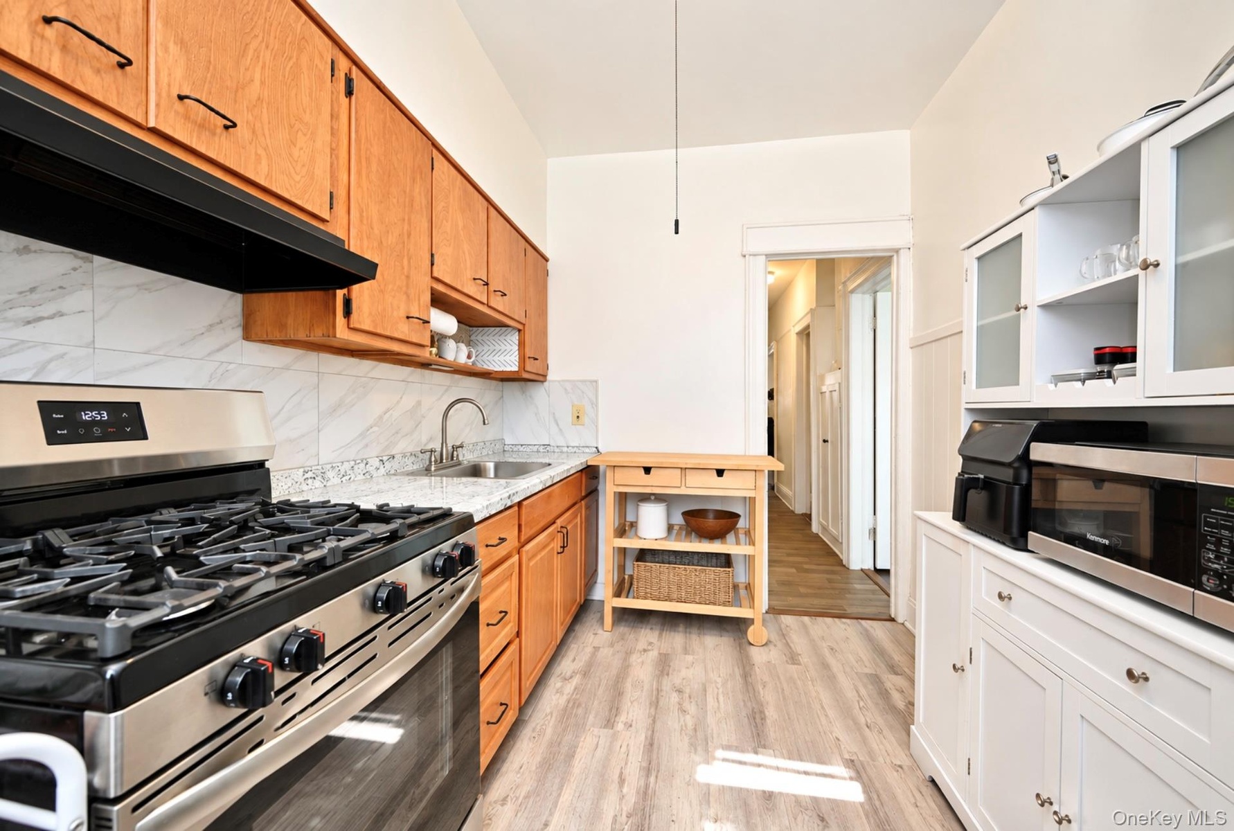 2nd. Floor: Kitchen featuring natural wood-finish cabinetry, stone-patterned countertops, a stainless steel gas range, wood-finish flooring, and white