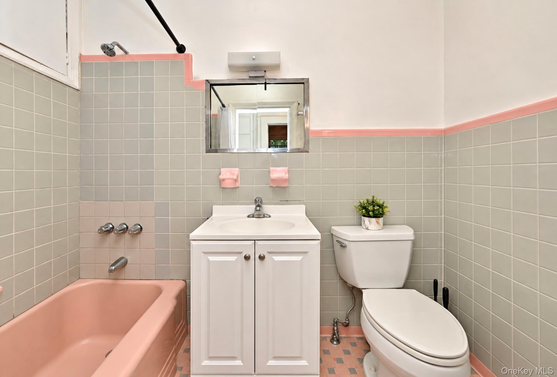 2nd. Floor: Bathroom featuring pastel tile wainscoting with accent trim, a pink porcelain soaking tub, white vanity cabinet with a integrated sink, wa