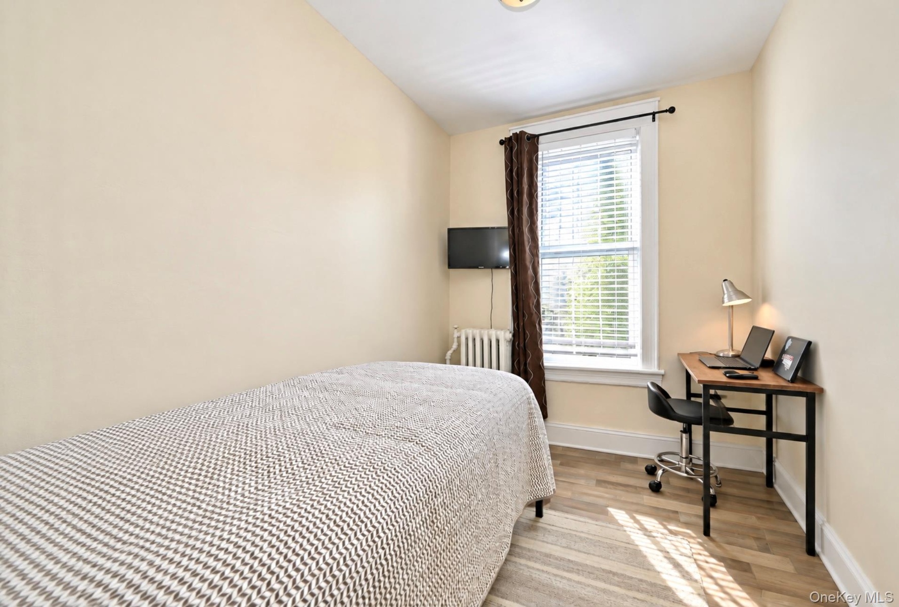 2nd. Floor: Neutral-toned walls, wood-finish flooring, a single-hung window with casing, and a classic metal radiator