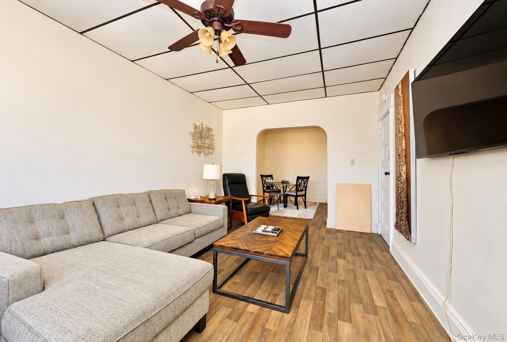 2nd. Floor: Room featuring wood-finish flooring, a suspended grid ceiling, a ceiling fan with integrated lighting, and an arched entryway