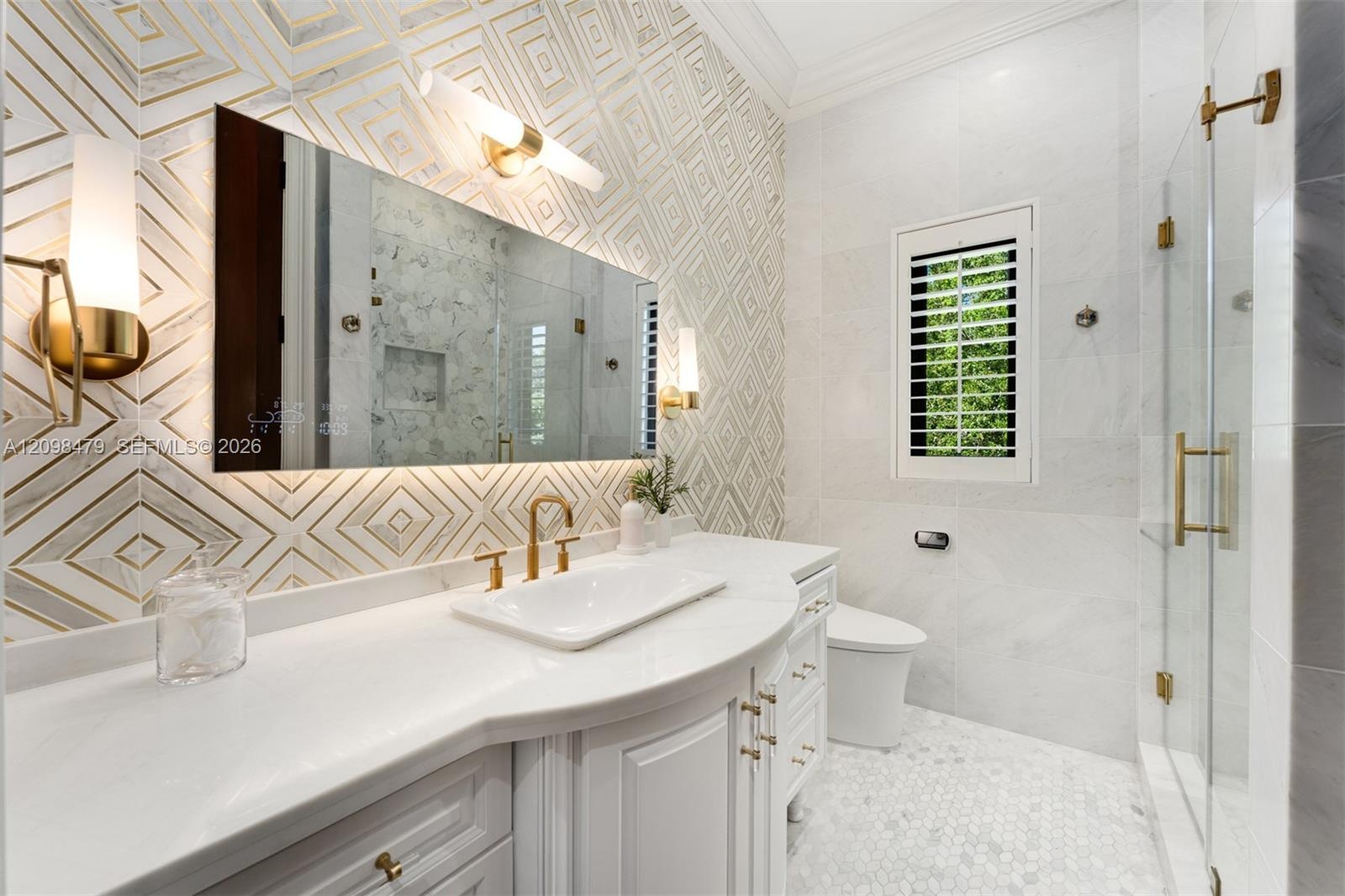 Custom vanity with a curved countertop, integrated sink, and gold-finish fixtures