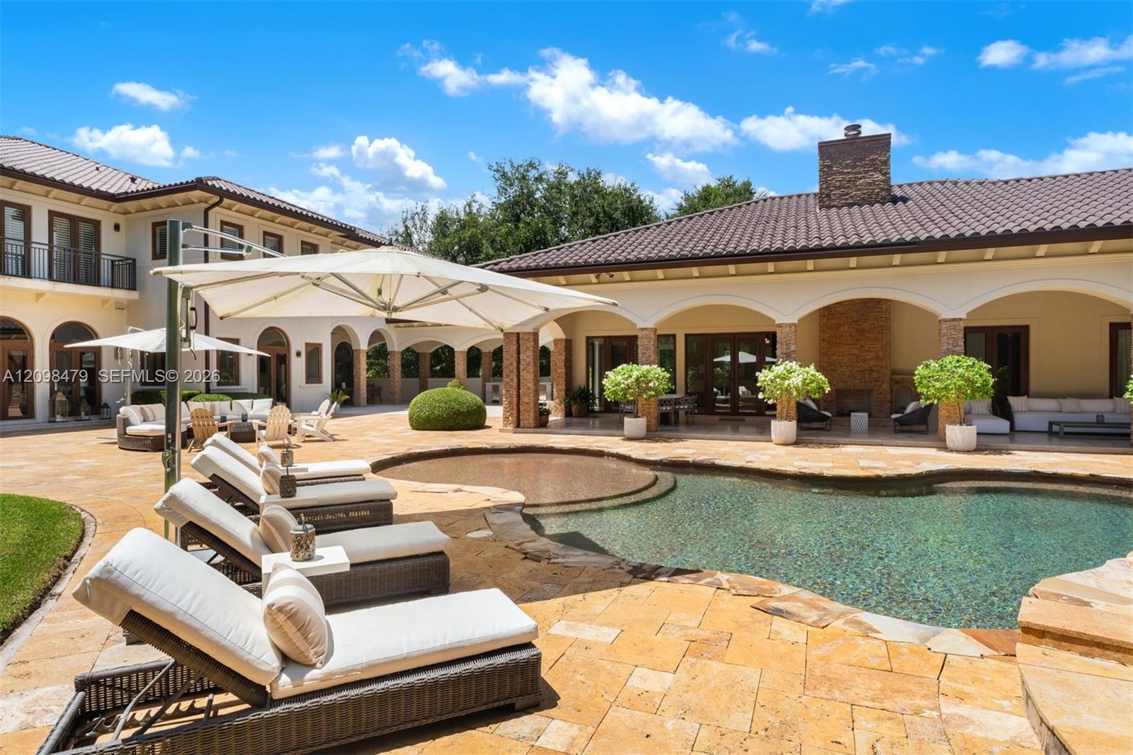 Expansive outdoor living area featuring a freeform swimming pool, integrated spa, and extensive paver patio