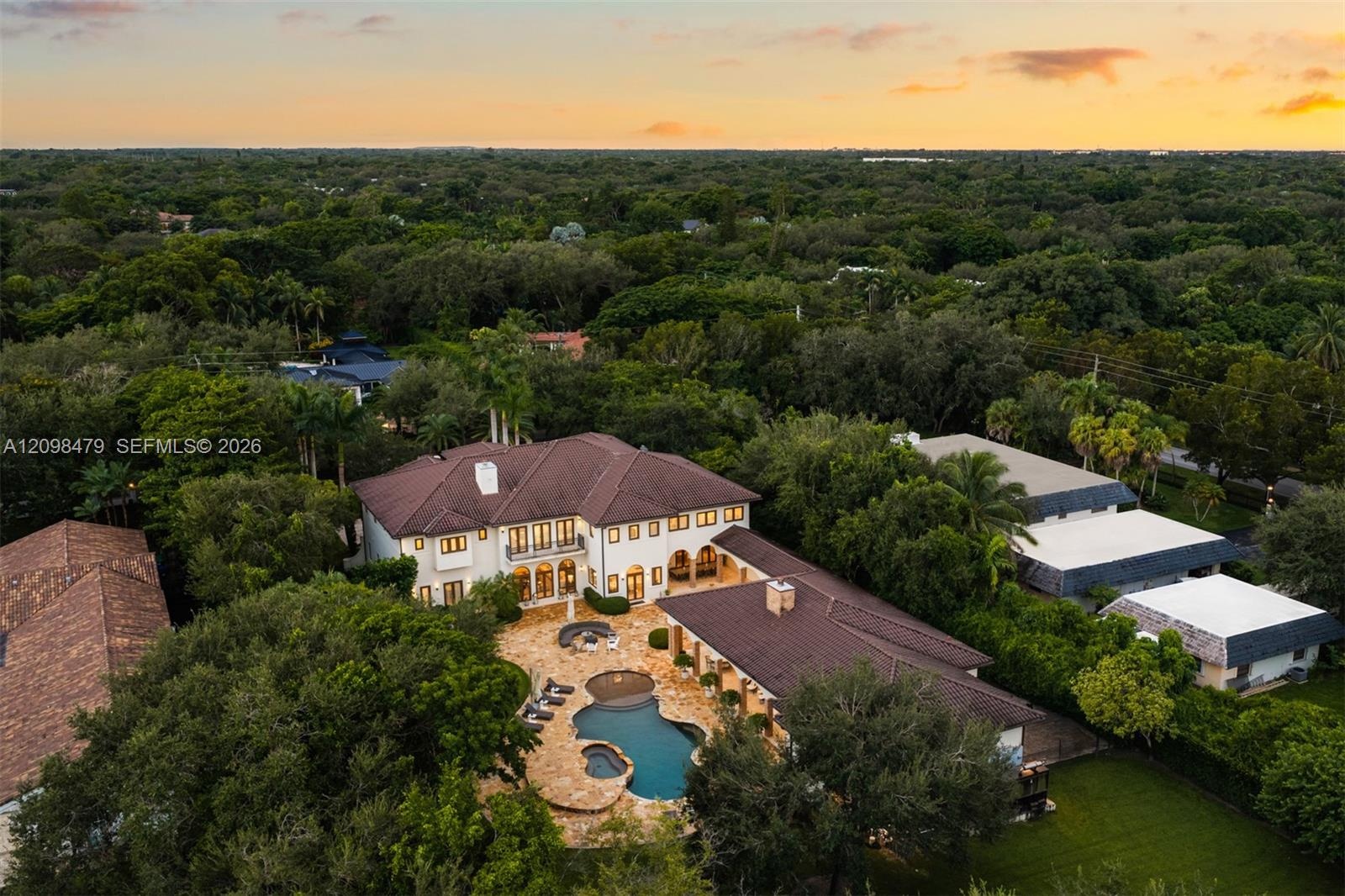 Aerial perspective of an expansive residence featuring a multi-gabled tile roof, stone-paved pool deck, custom-shaped swimming pool with integrated sp