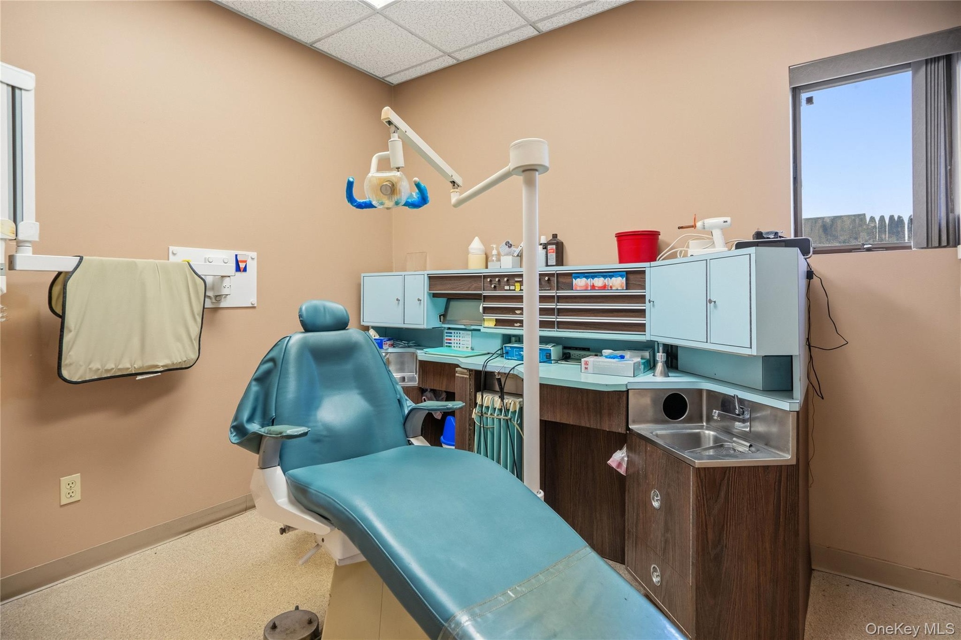 Examination room featuring custom built-in cabinetry, a stainless steel sink, tile flooring, and a drop ceiling