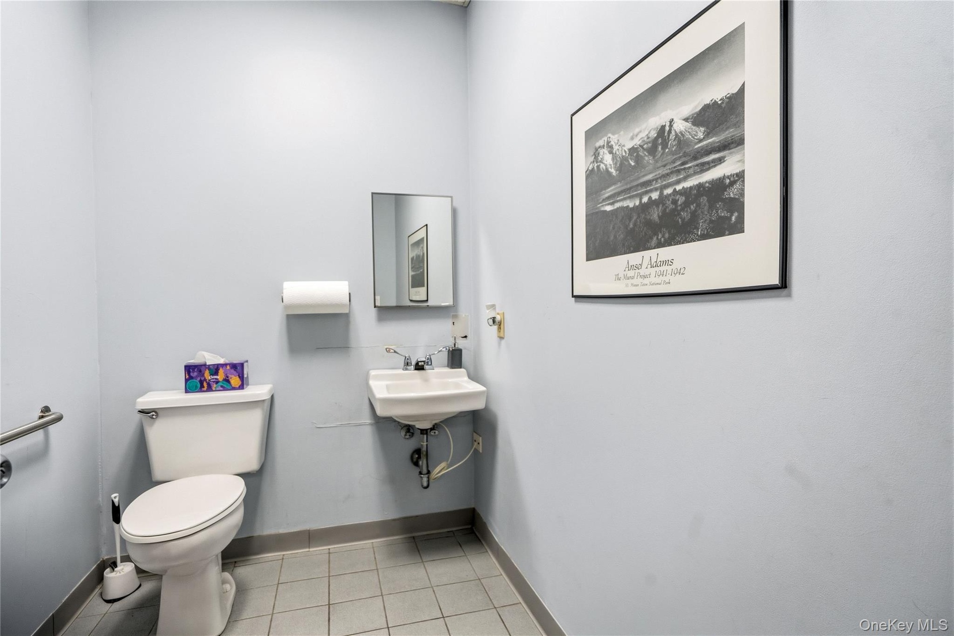 Wall-mounted porcelain sink with dual-handle faucet, rectangular medicine cabinet, and tiled flooring