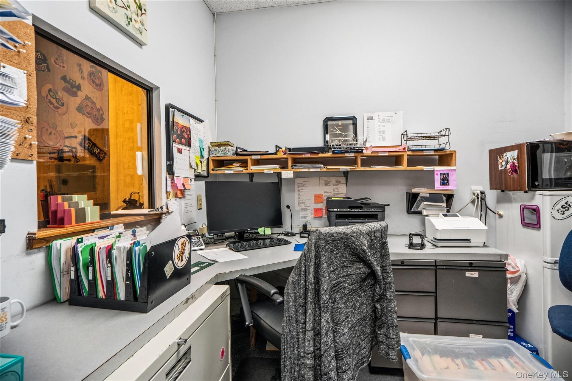 Built-in workstation featuring a wrap-around laminate desk surface, integrated drawer storage, and overhead wall-mounted shelving
