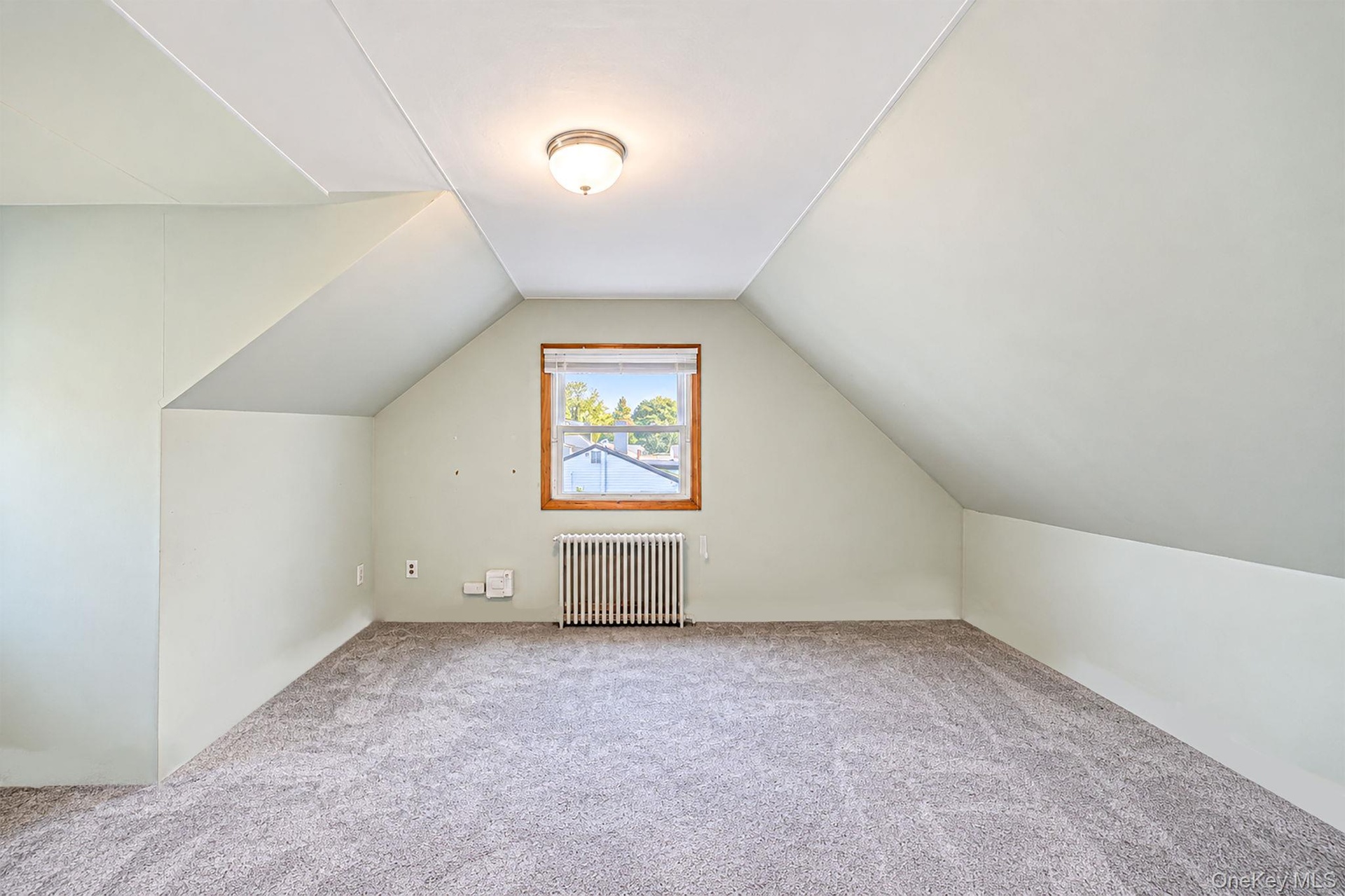 2nd floor bedroom featuring, wall-to-wall carpeting, a central window with wood trim, and a classic metal radiator