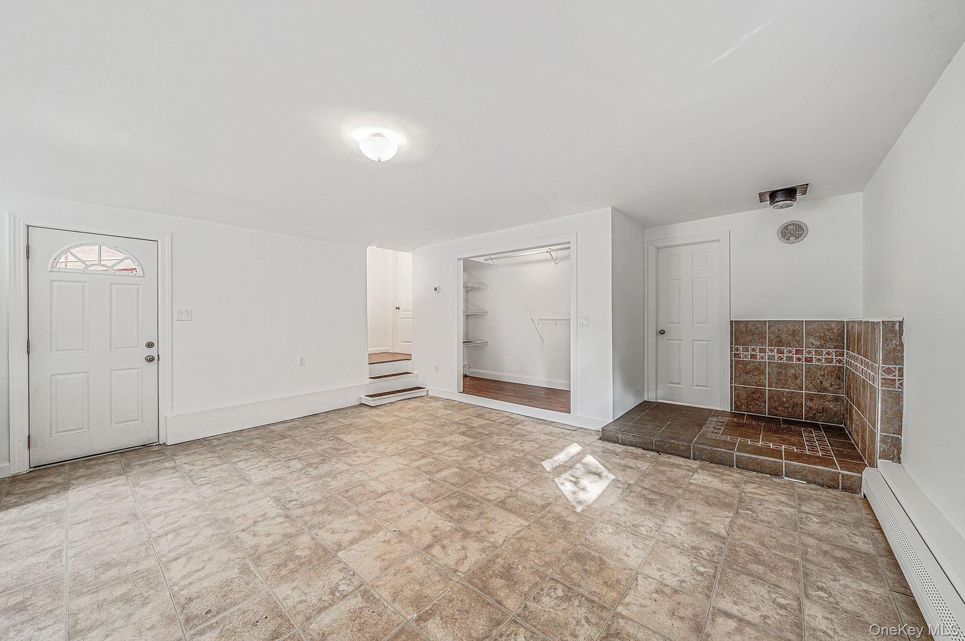 Interior room featuring vinyl tile flooring, a raised tiled hearth is outfitted for a wood burning stove (not included), a built-in walk-in closet, an