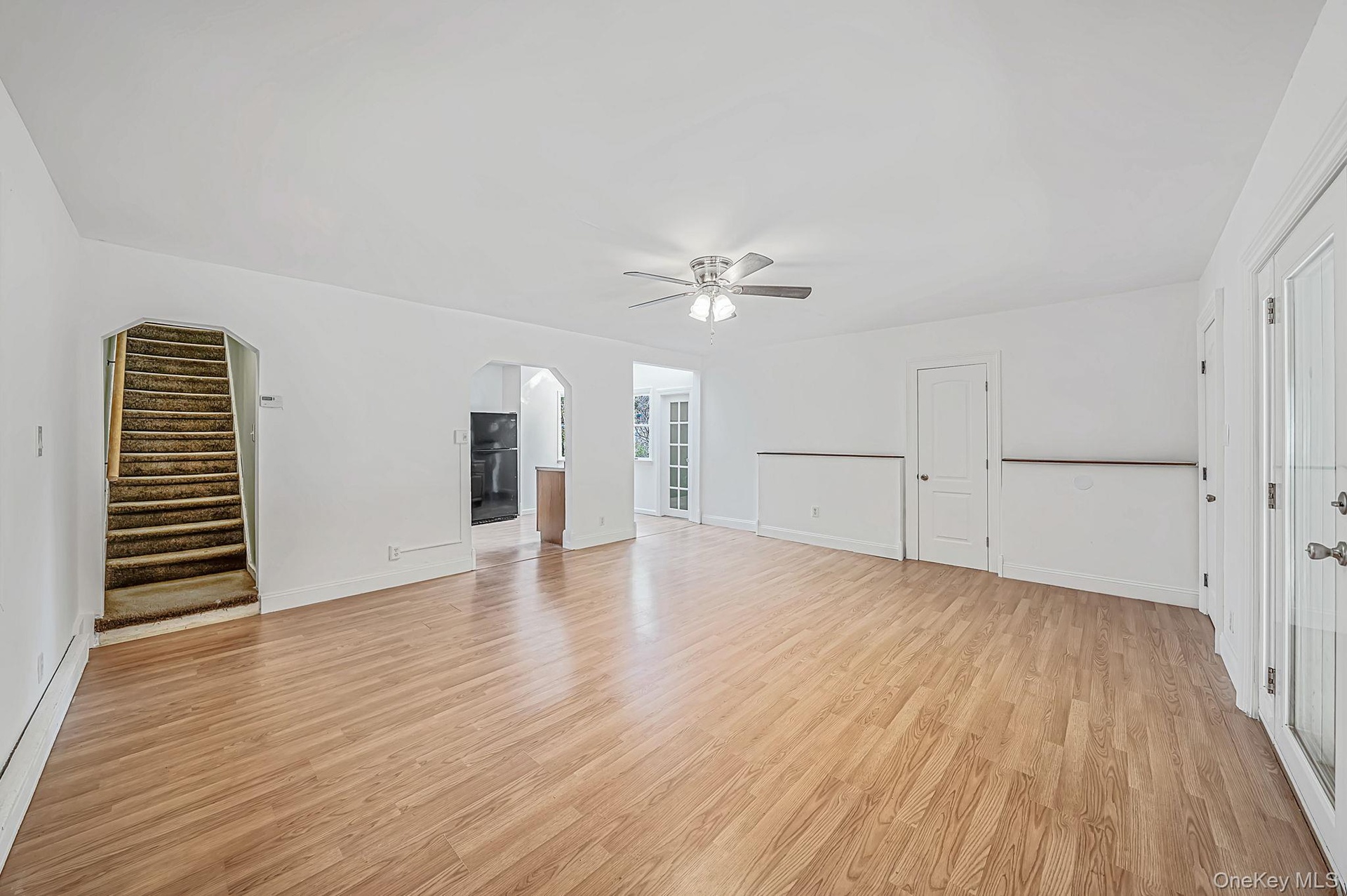 Open floor plan featuring laminate flooring, archway entrance leads to second floor.