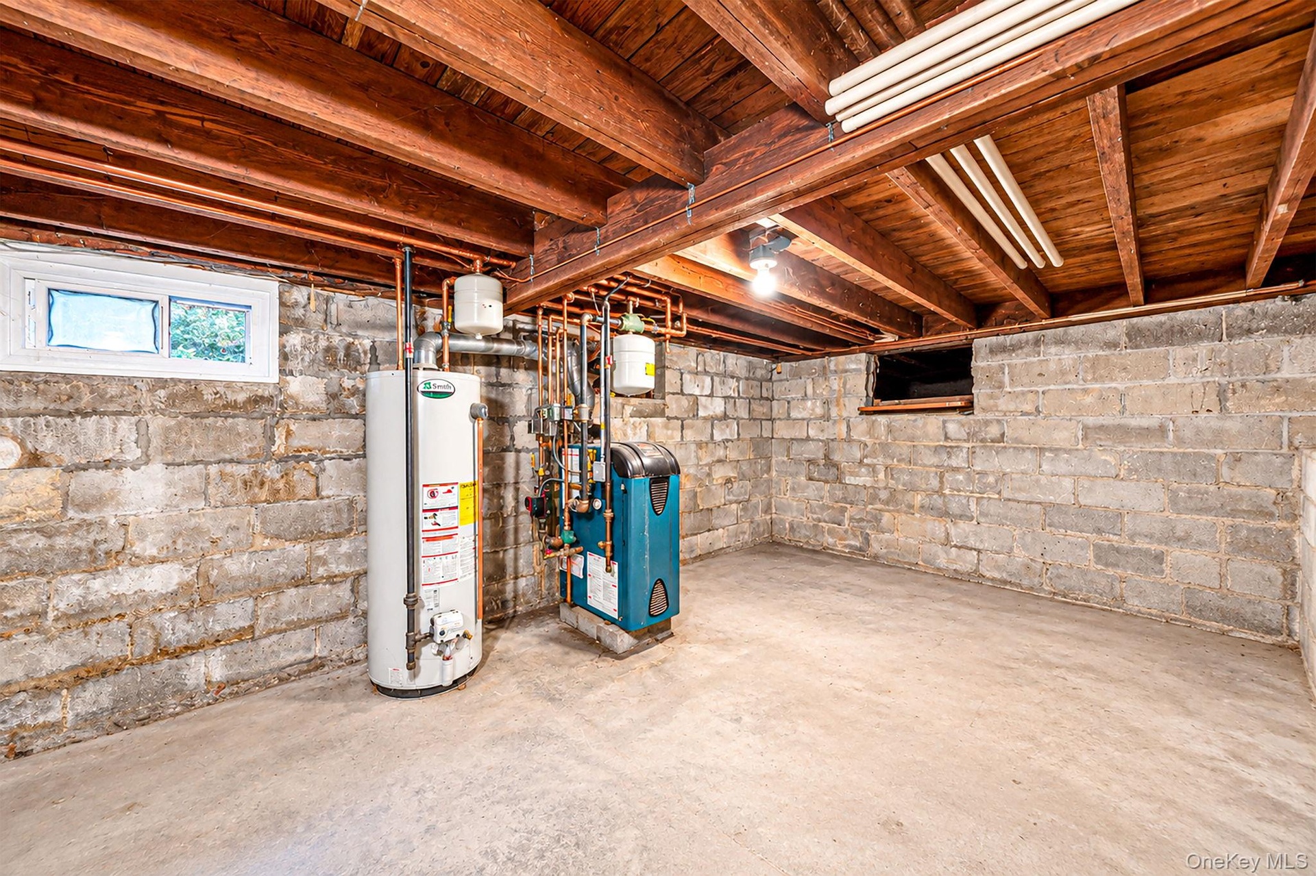 Utility area featuring exposed wood ceiling joists, concrete block walls, concrete flooring, water heater, and boiler system