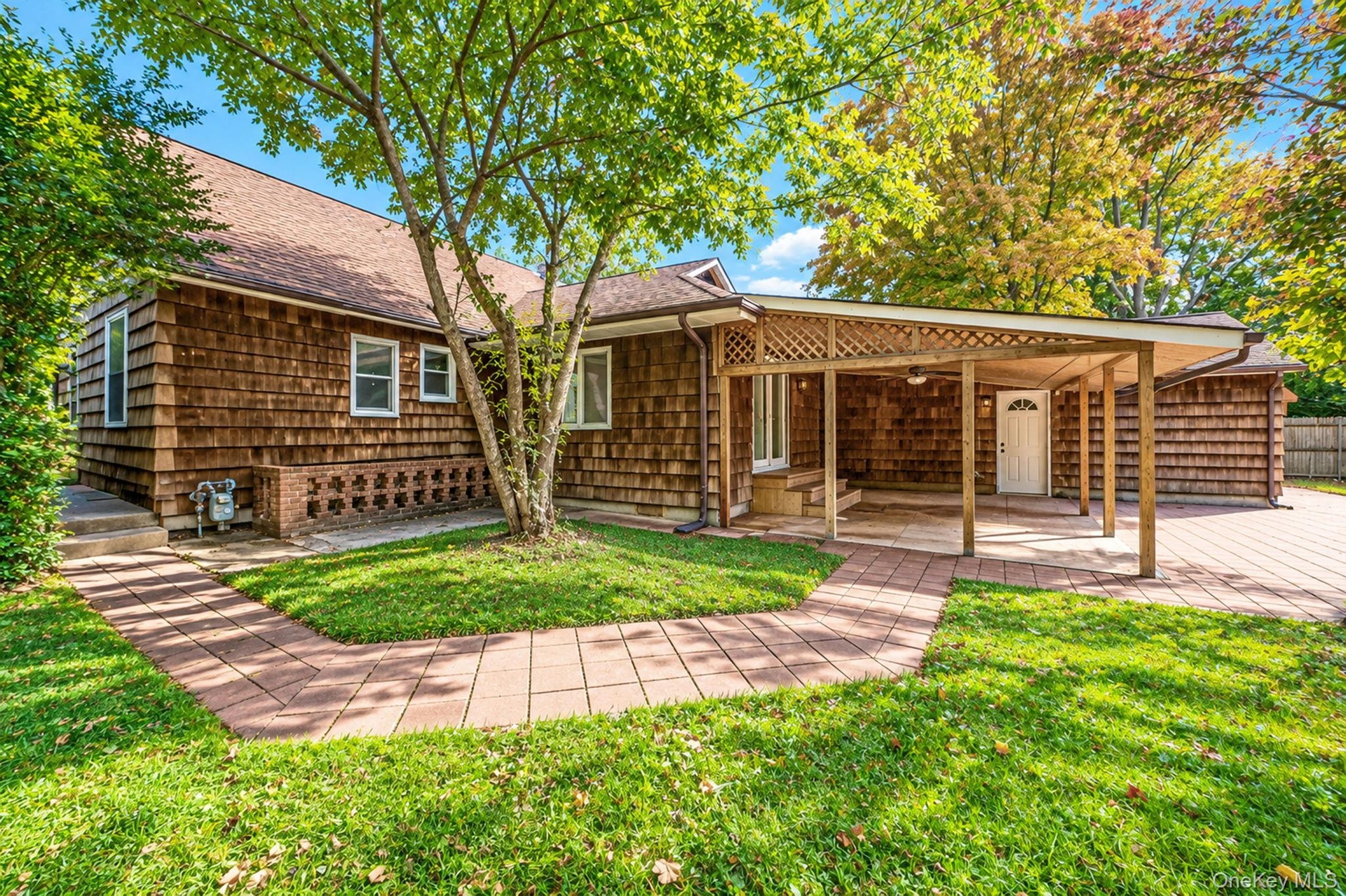 Exterior featuring cedar shingle siding, covered patio, and paved walkway
